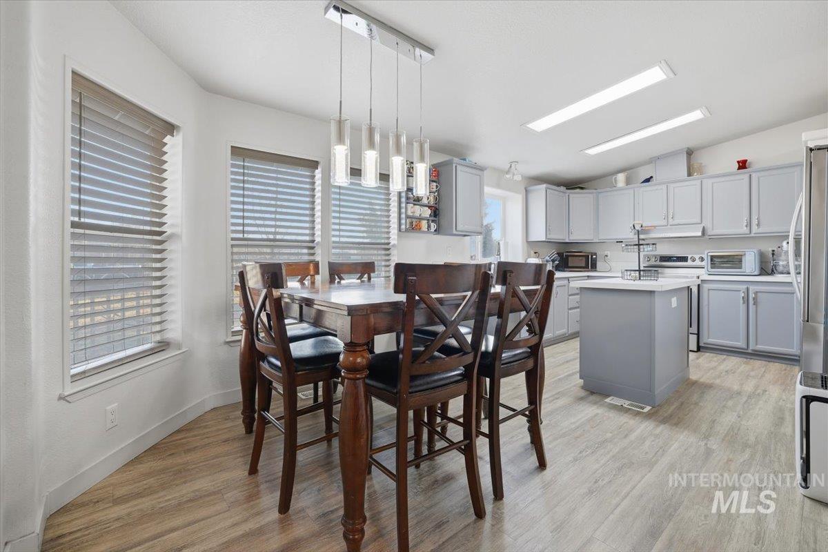 Dining area featuring light wood-style floors and vaulted ceiling