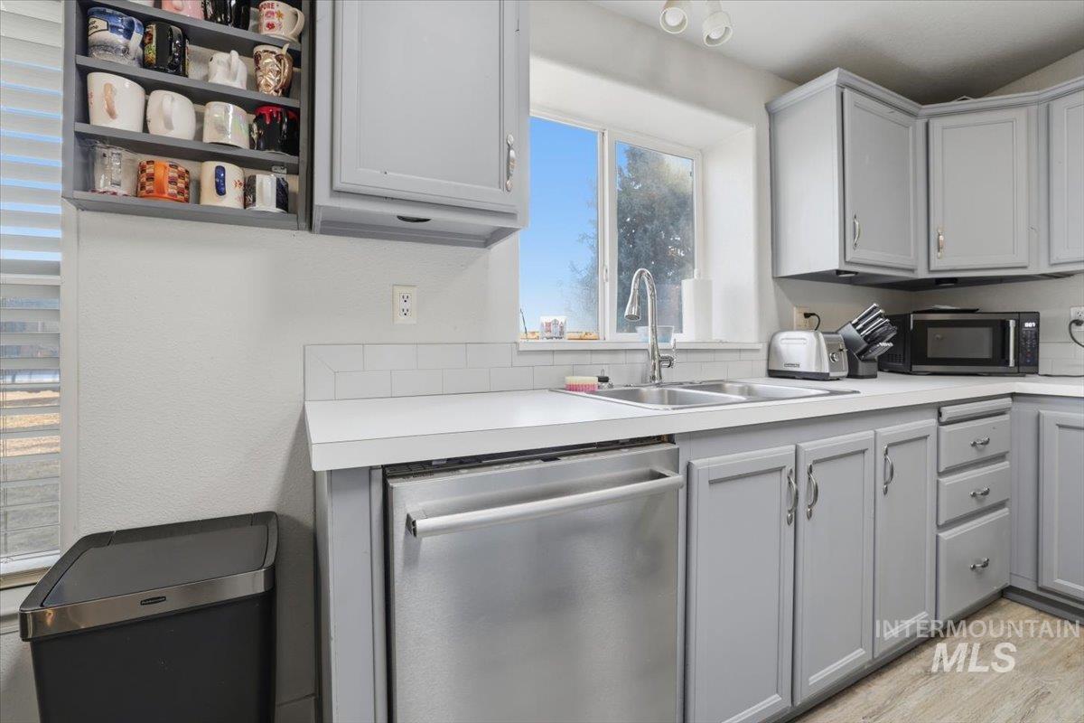 Kitchen featuring gray cabinets, appliances with stainless steel finishes, light countertops, and light wood-style floors