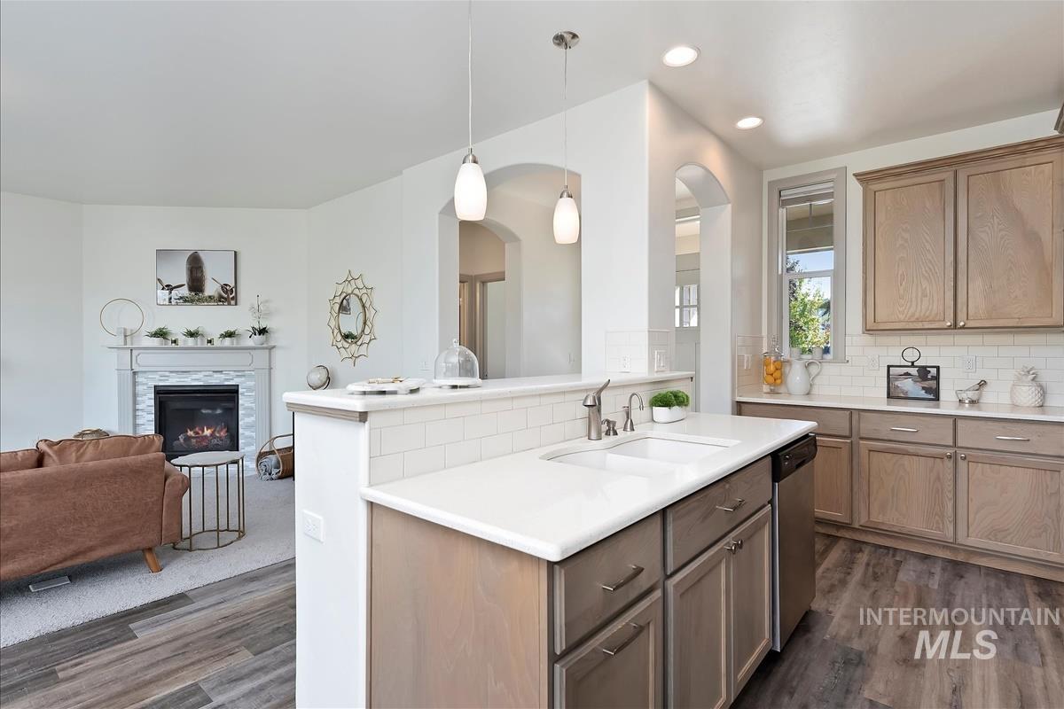 Kitchen with pendant lighting, open floor plan, dark wood-type flooring, tasteful backsplash, and a tile fireplace