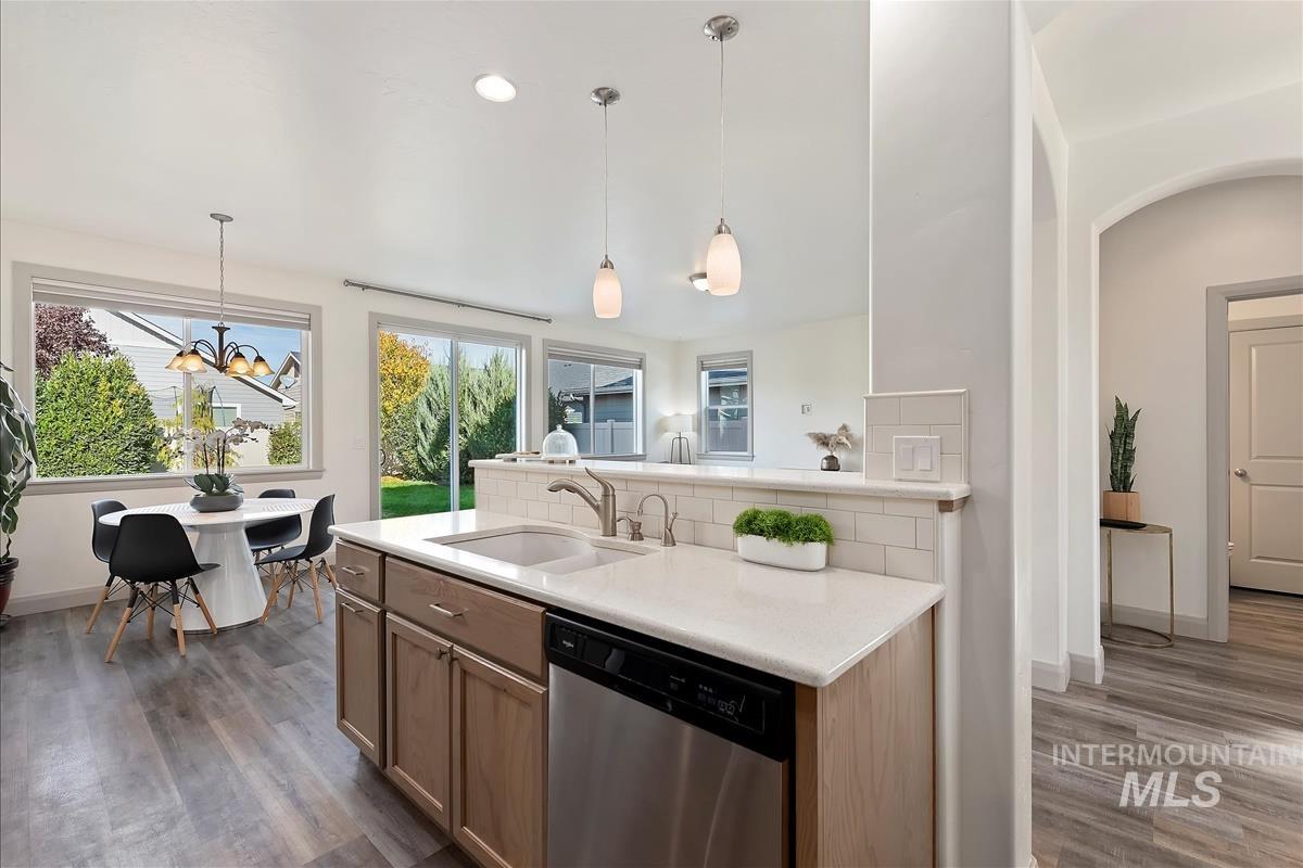 Kitchen with dishwasher, decorative light fixtures, a chandelier, and dark wood finished floors