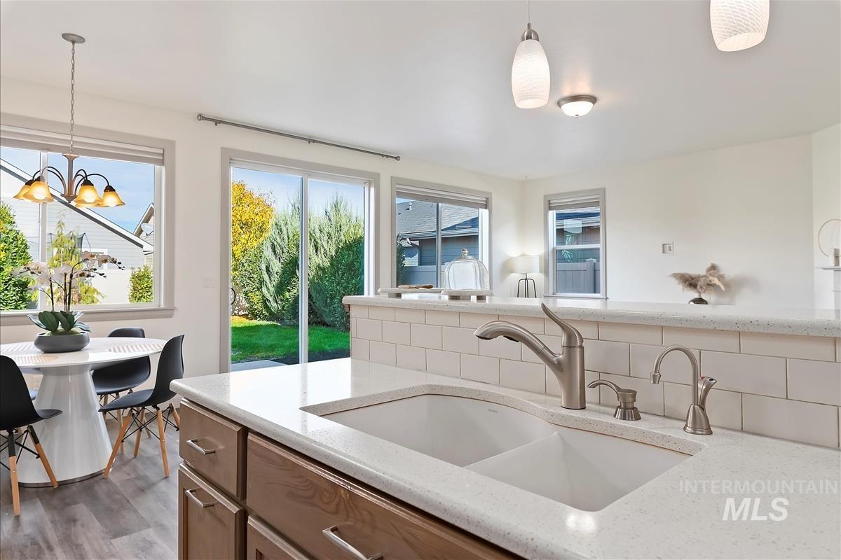 Kitchen featuring light stone countertops, hanging light fixtures, and backsplash