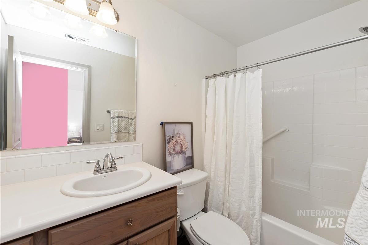 Bathroom featuring vanity and shower / bathtub combination with curtain