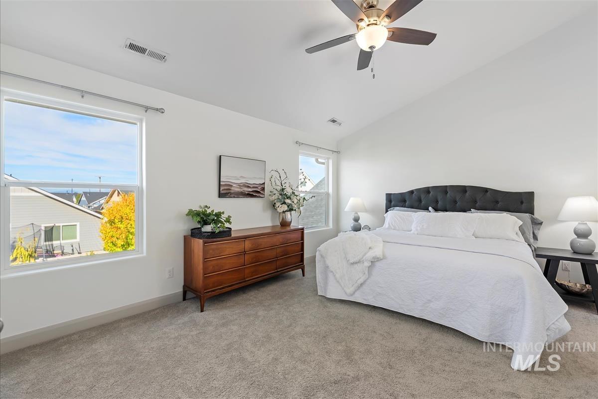 Bedroom with vaulted ceiling, carpet flooring, and ceiling fan