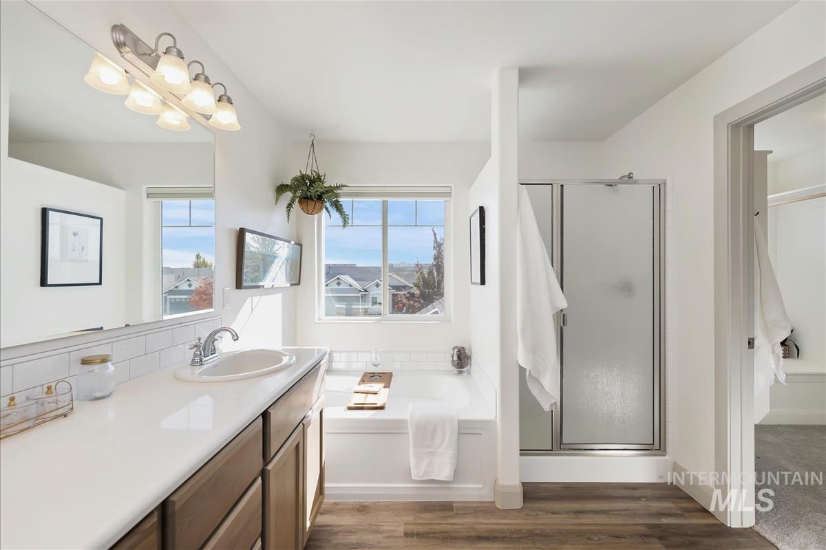 Full bath with a garden tub, a stall shower, dark wood-style flooring, and healthy amount of natural light