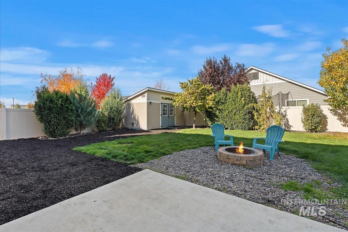 Fenced backyard featuring an outbuilding, an outdoor fire pit, and a patio