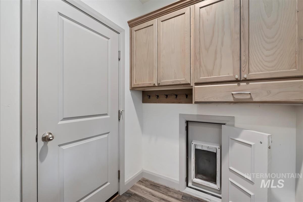 Door between garage and home with discrete dog door into garage to dog run. Mud room has hooks and cabinets.