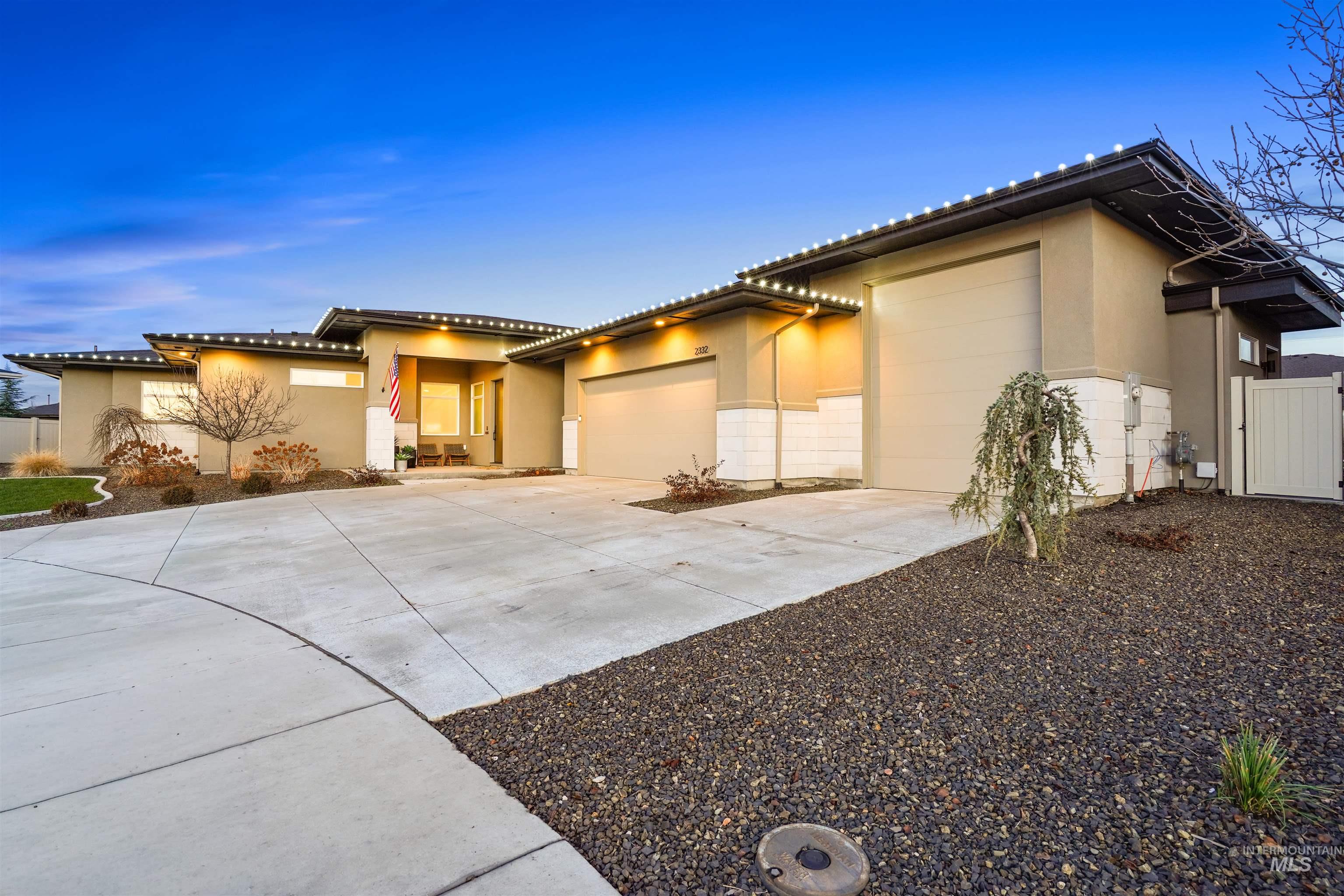 Prairie-style home featuring an attached garage, driveway, stucco siding, and a tile roof