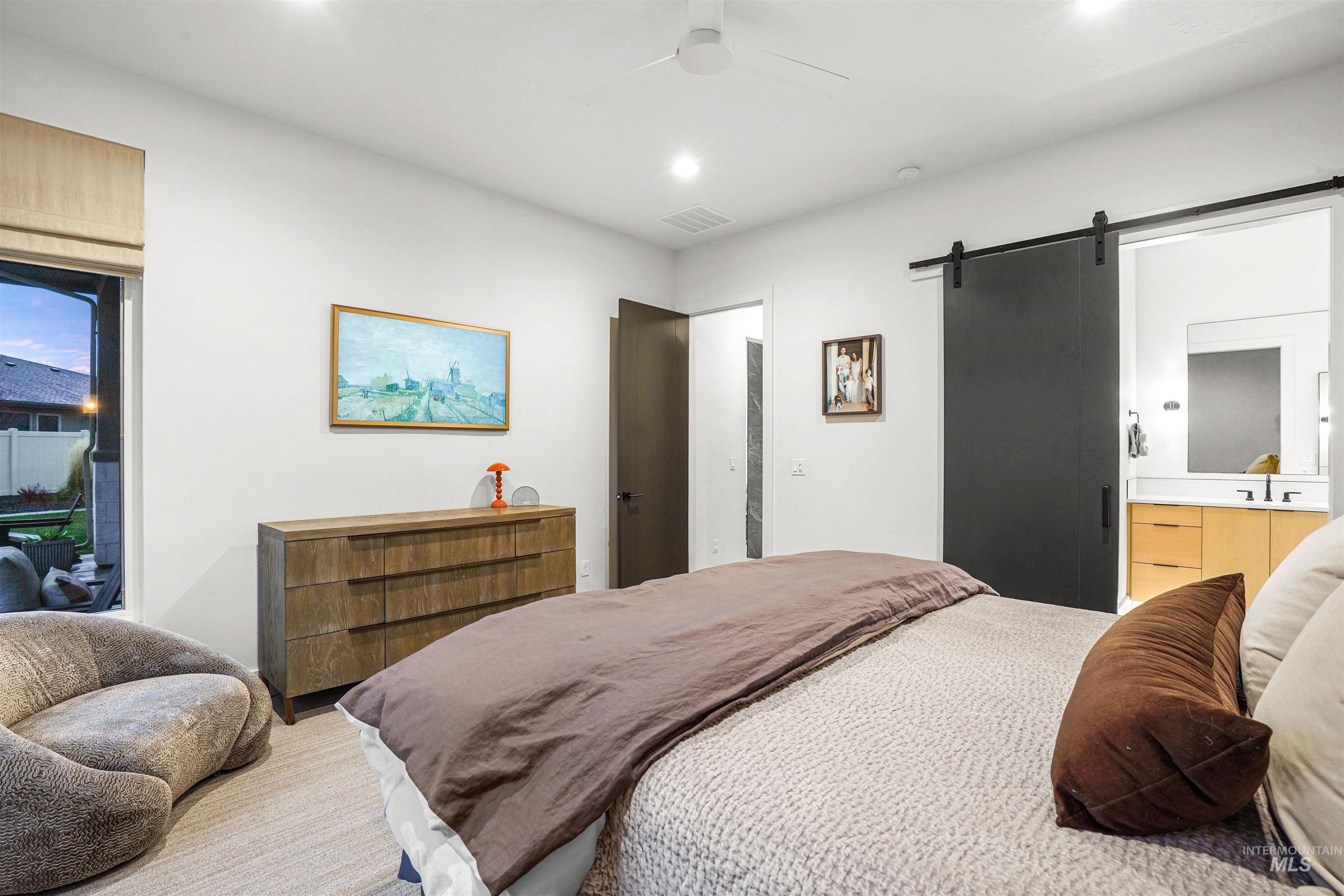 Bedroom featuring a barn door, ceiling fan, ensuite bathroom, and recessed lighting