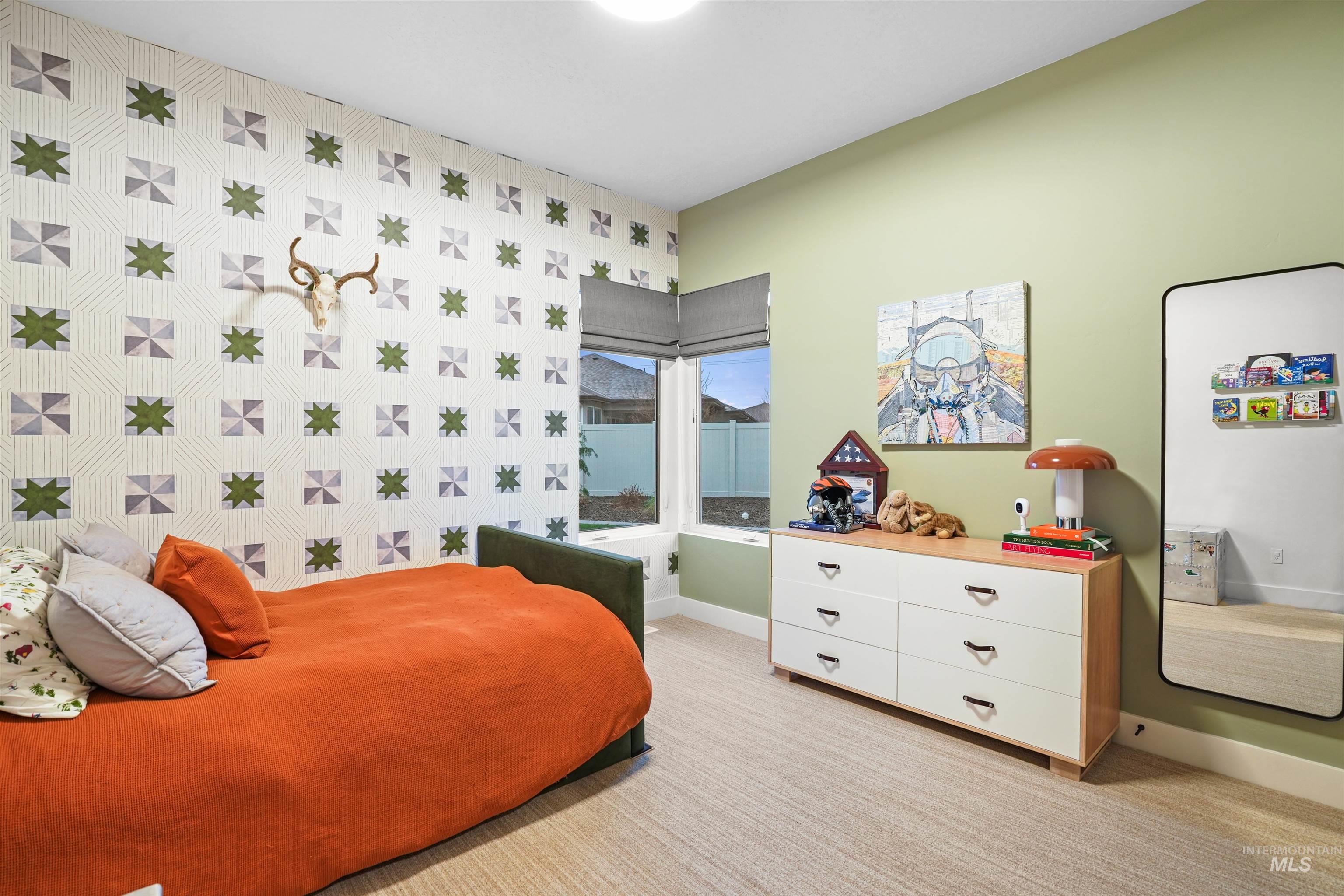 Bedroom featuring wallpapered walls, light carpet, and an accent wall