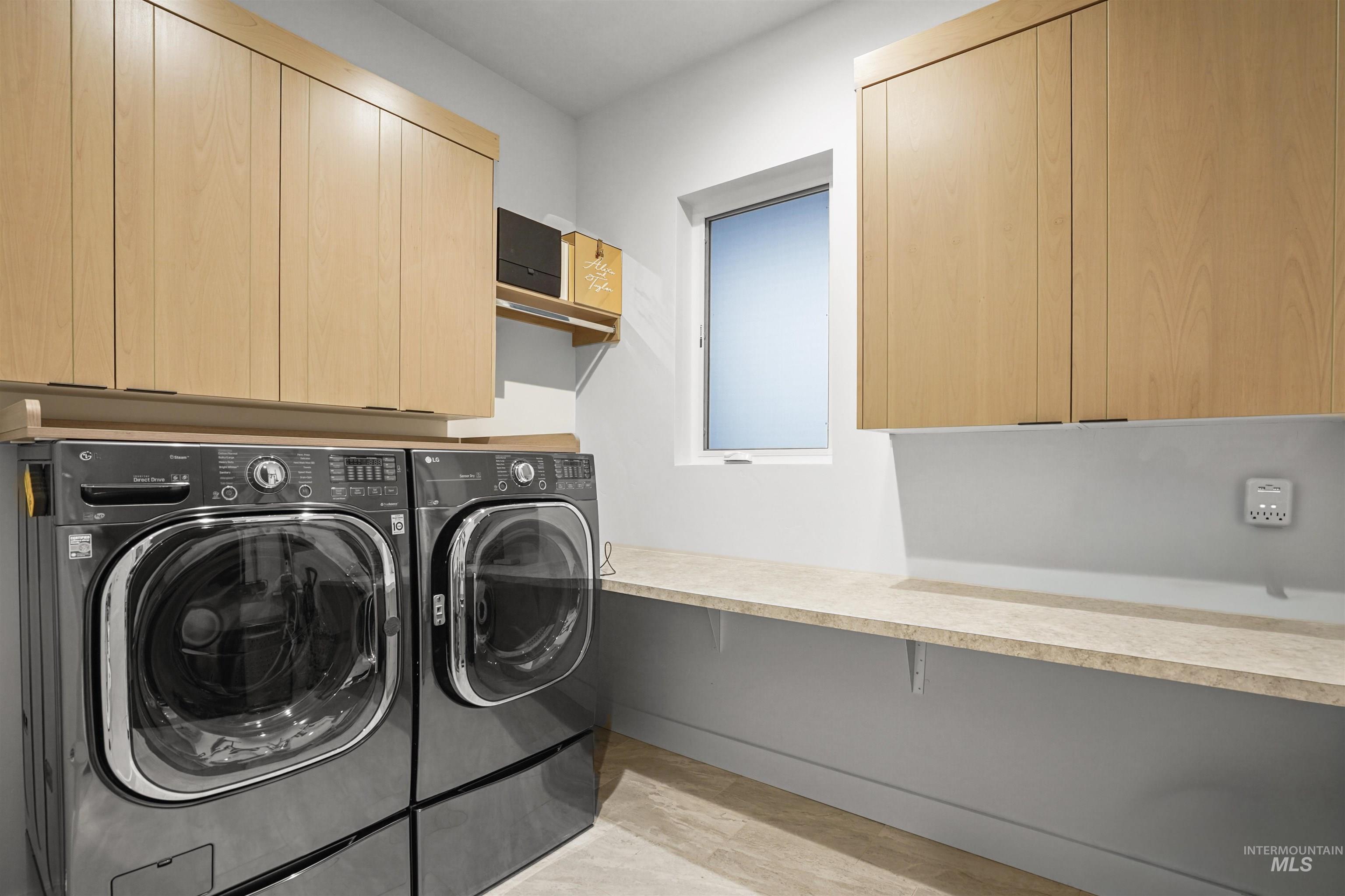 Laundry room featuring cabinet space, washing machine and clothes dryer, and light wood finished floors