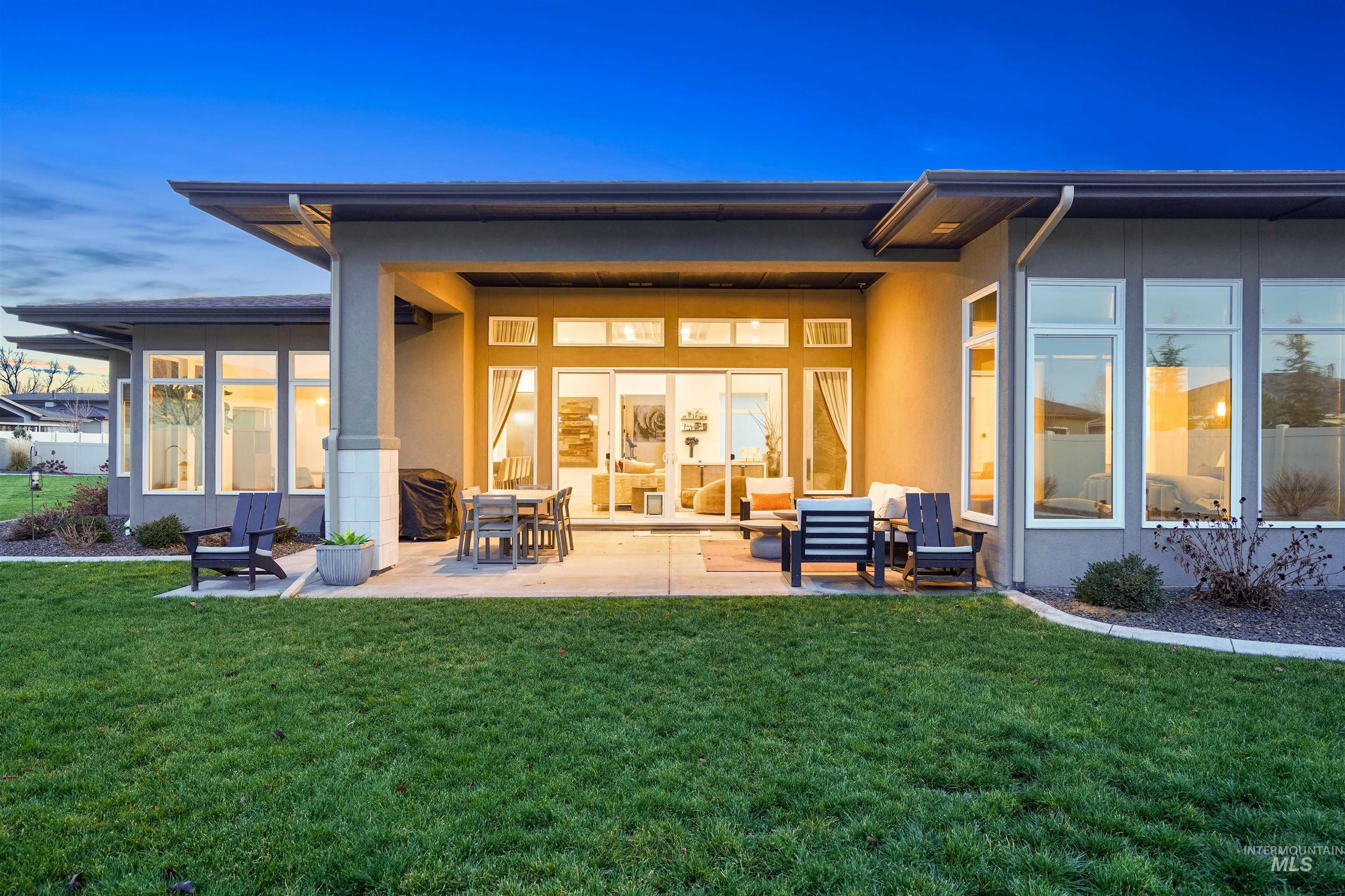 Back of house featuring a patio area, a lawn, and stucco siding
