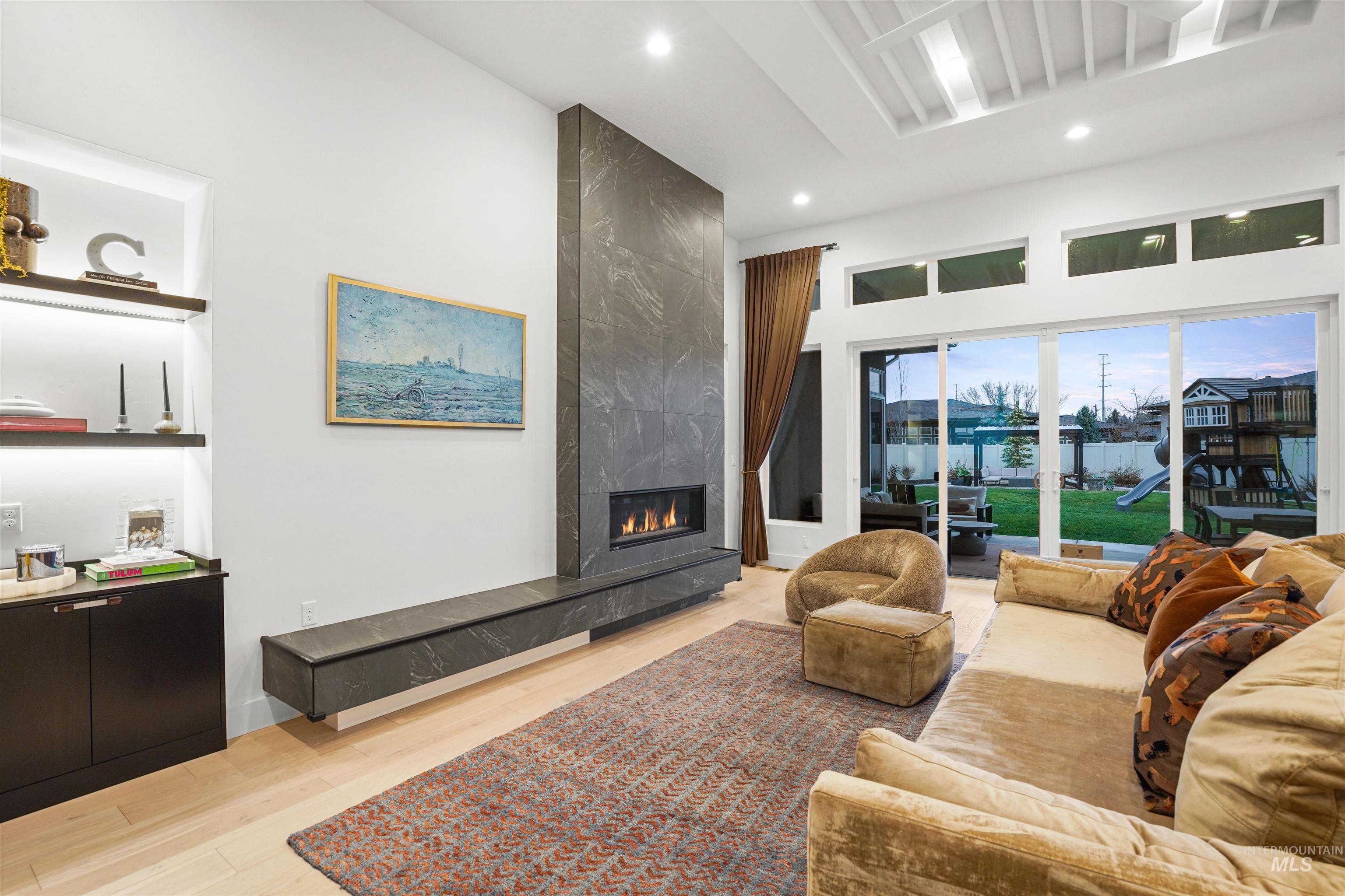 Living area with a high end fireplace, light wood-style floors, and recessed lighting