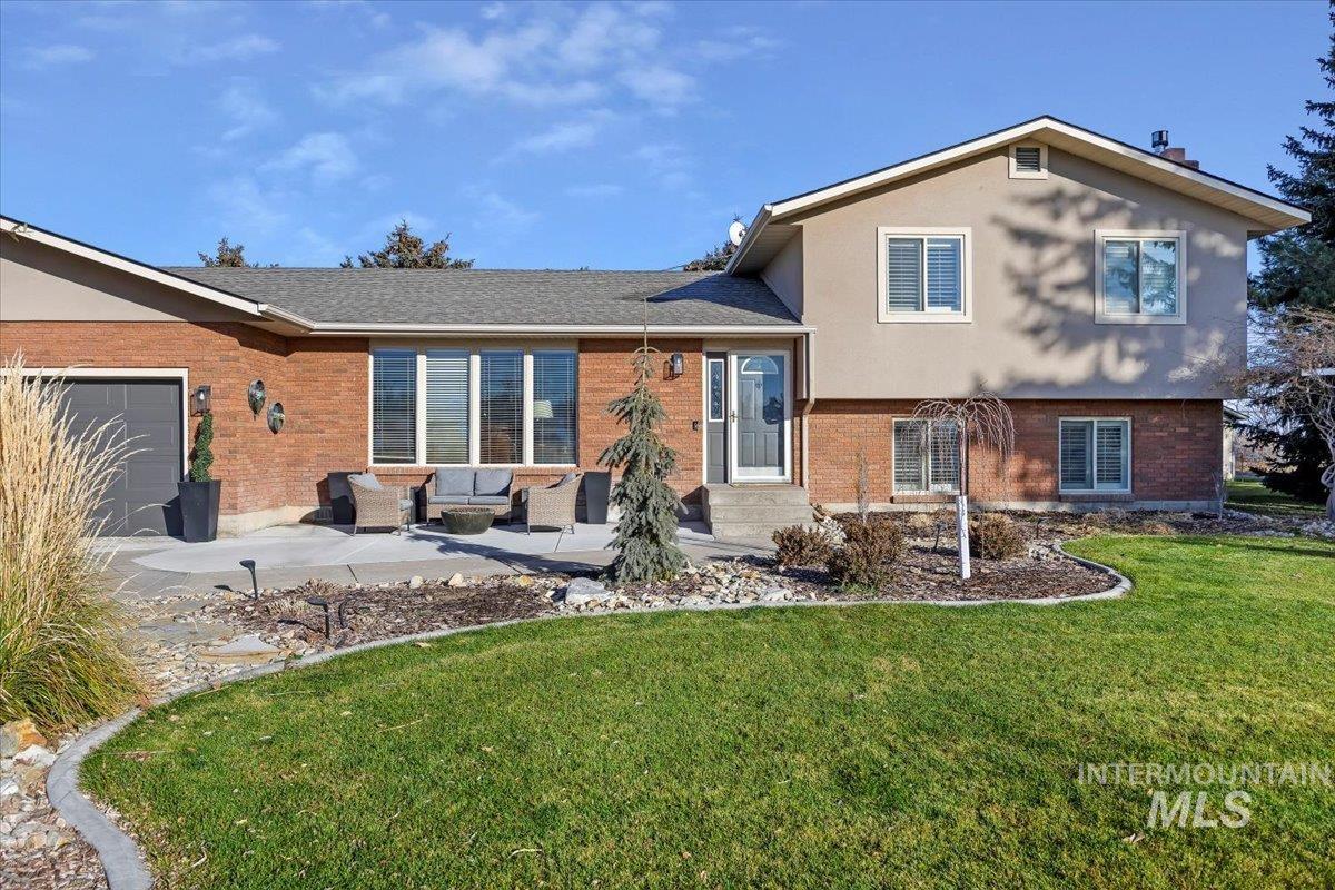 Rear view of house with a lawn, a patio area, brick siding, and an outdoor living space