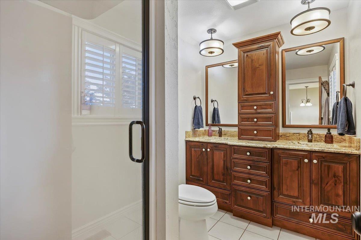 Bathroom with double vanity, a shower stall, and light tile patterned floors