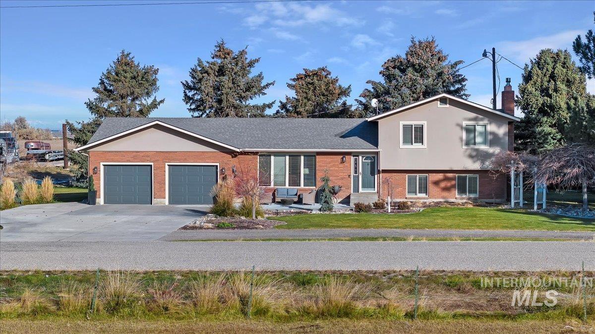 View of front facade with brick siding, an attached garage, concrete driveway, a front lawn, and a chimney