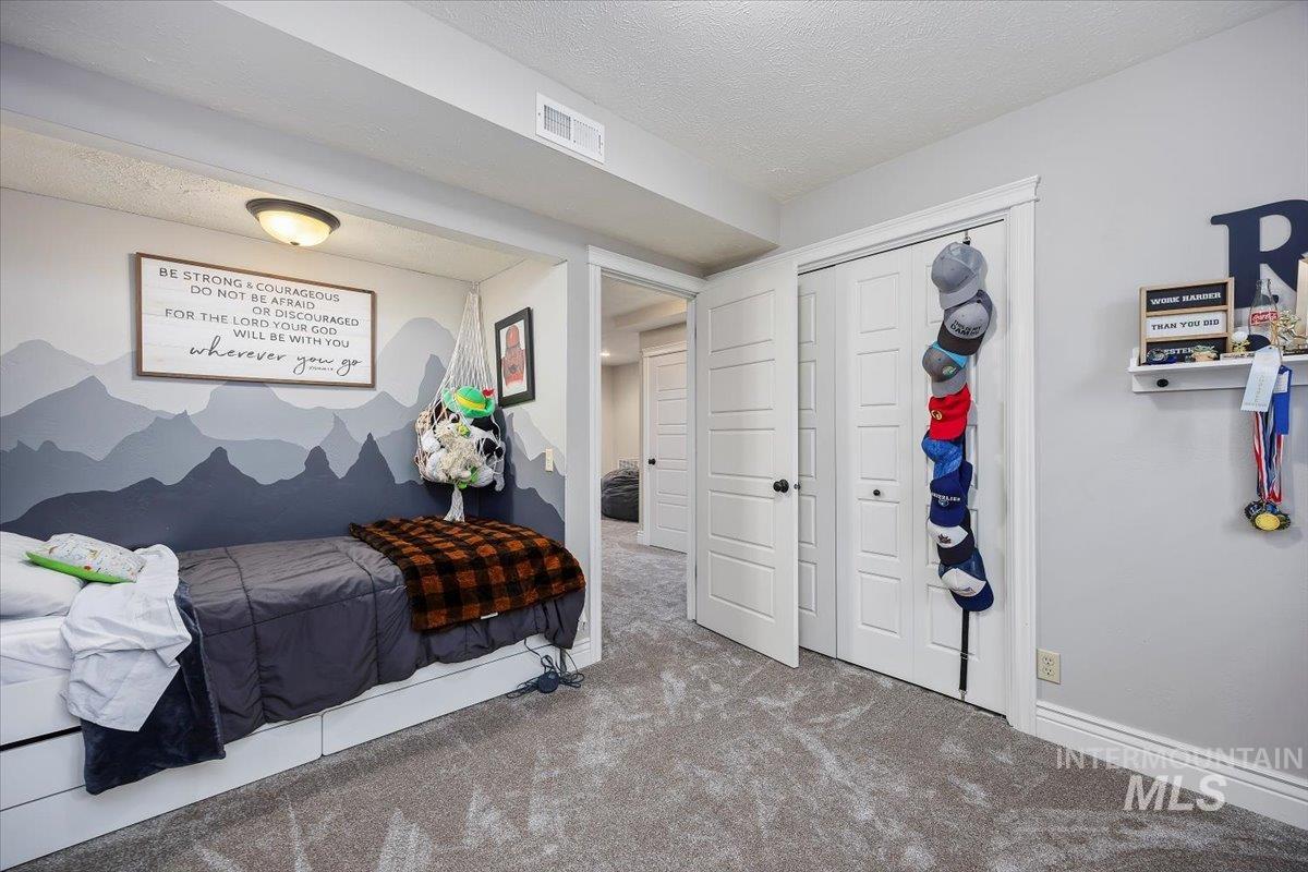 Carpeted bedroom with a textured ceiling and a closet