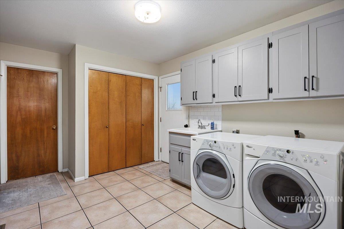 Laundry area with washing machine and clothes dryer, cabinet space, and light tile patterned flooring