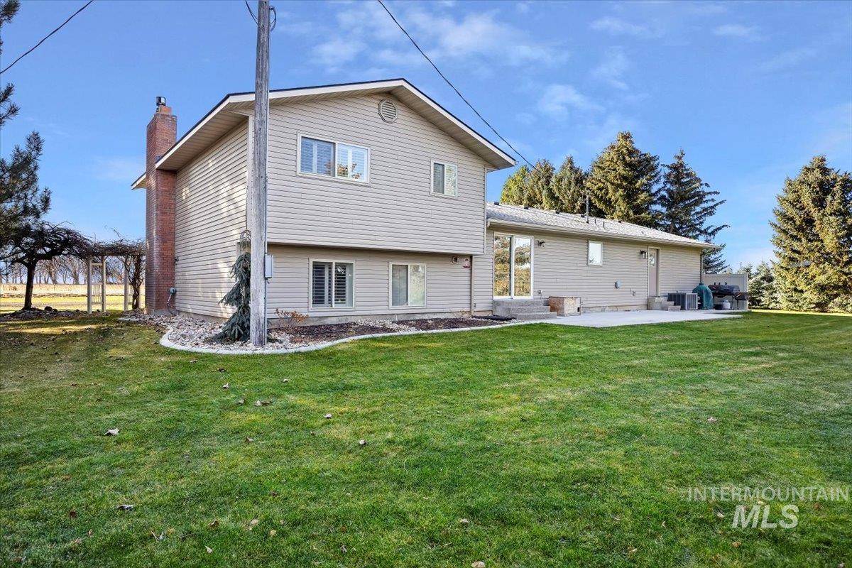 Rear view of property with a lawn, a chimney, and a patio area