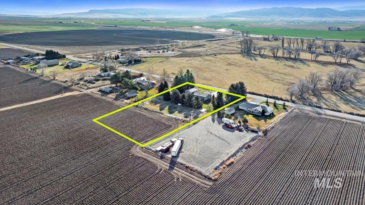 Overview of rural landscape with property parcel outlined and a mountainous background