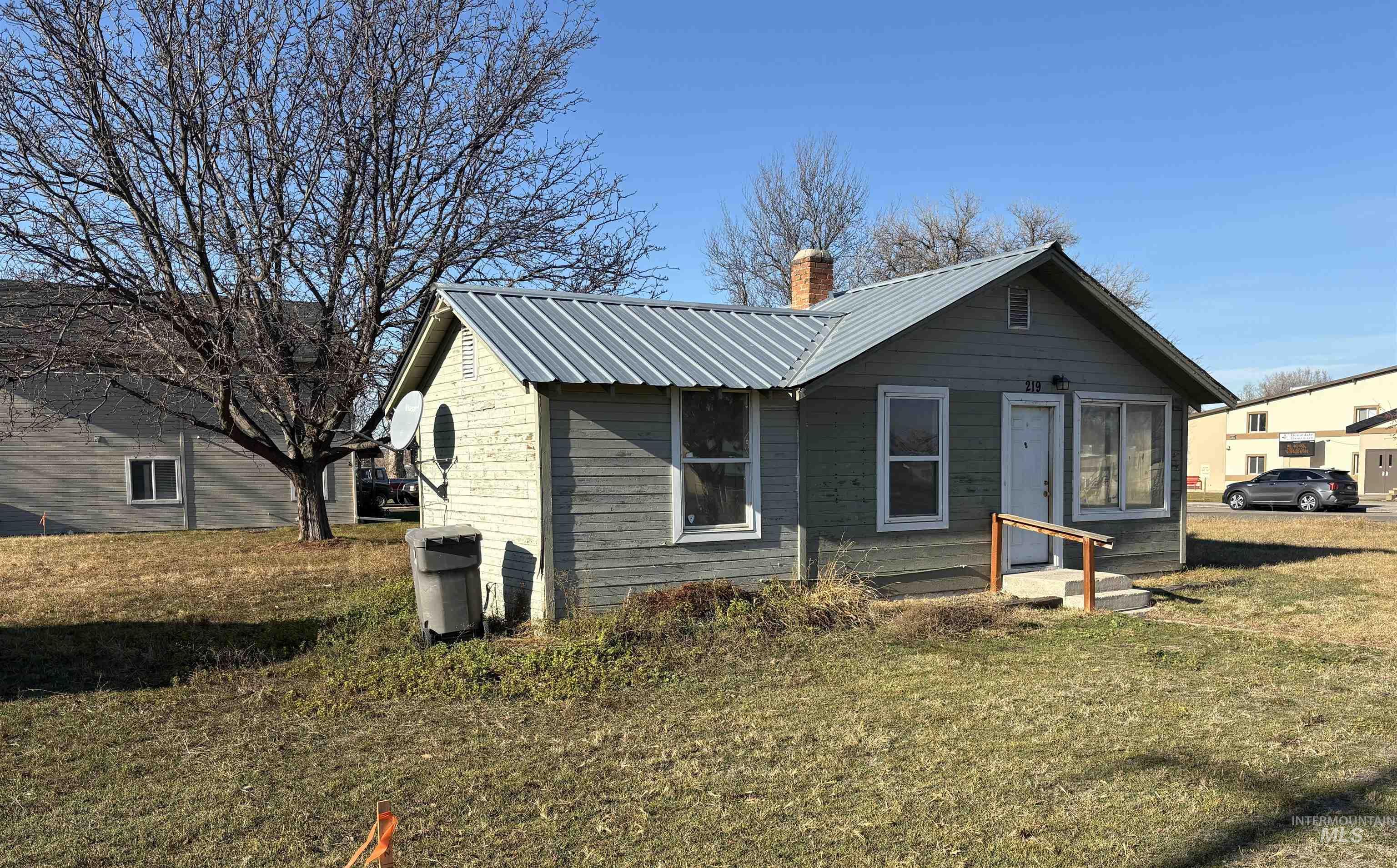 Rear view of property featuring a yard, a metal roof, and a chimney