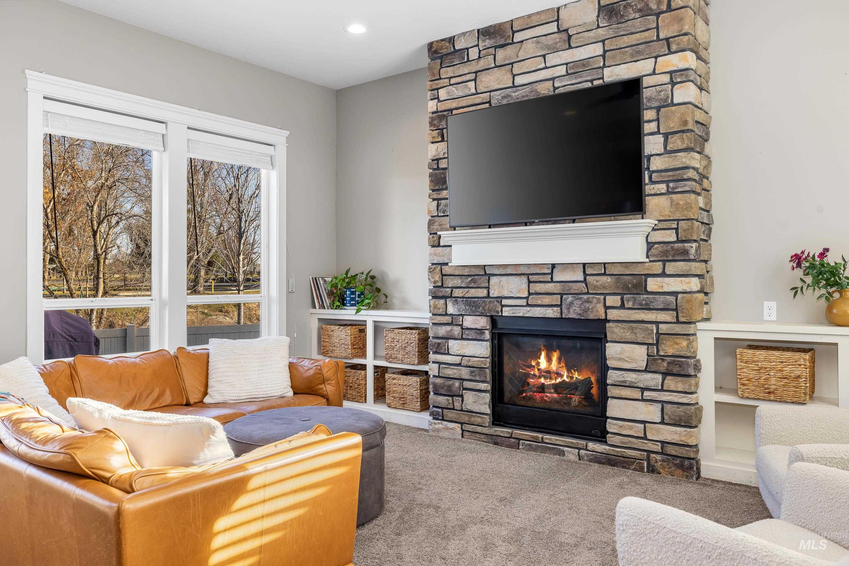 Living area featuring a stone fireplace and carpet