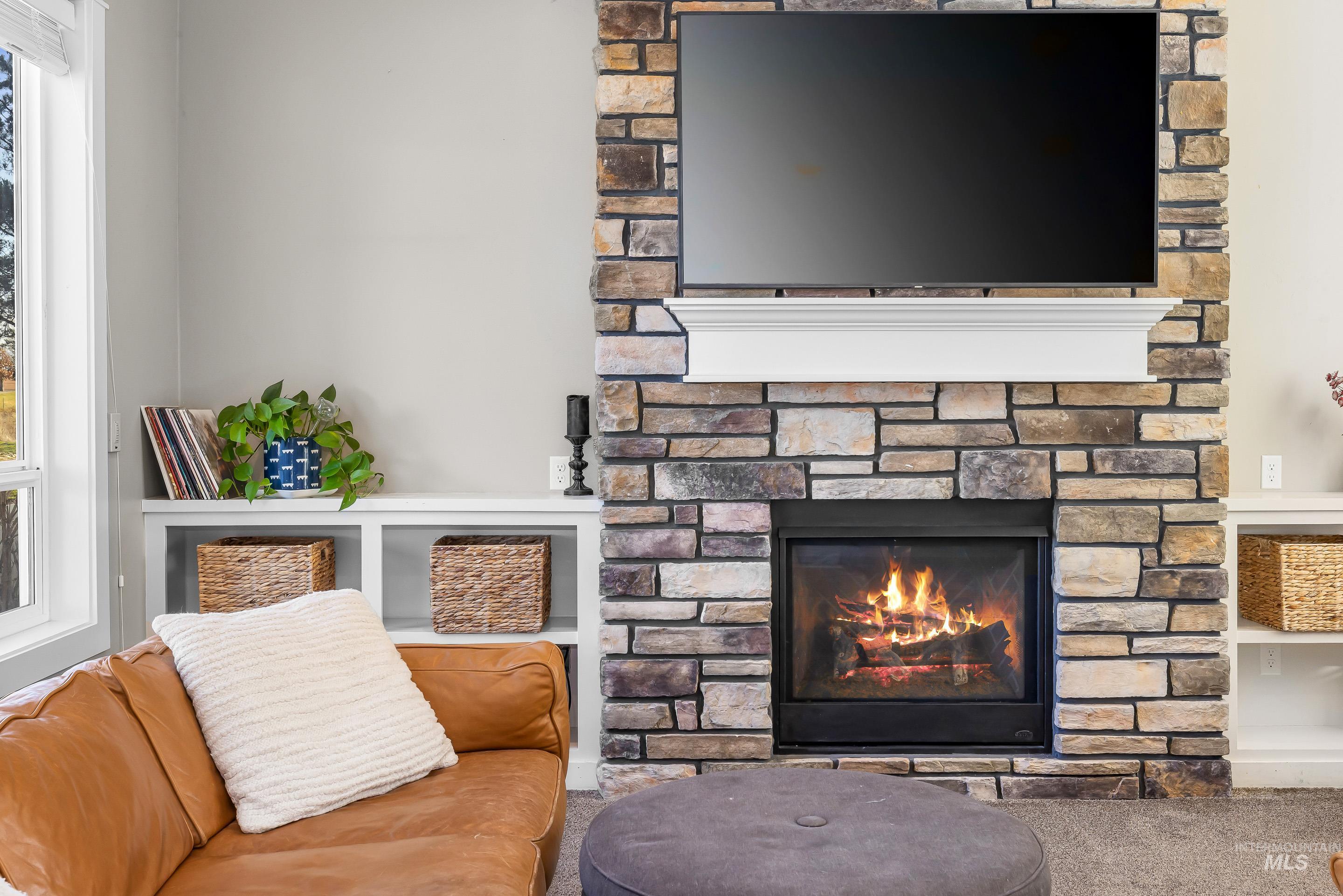 Living area with a stone fireplace and carpet