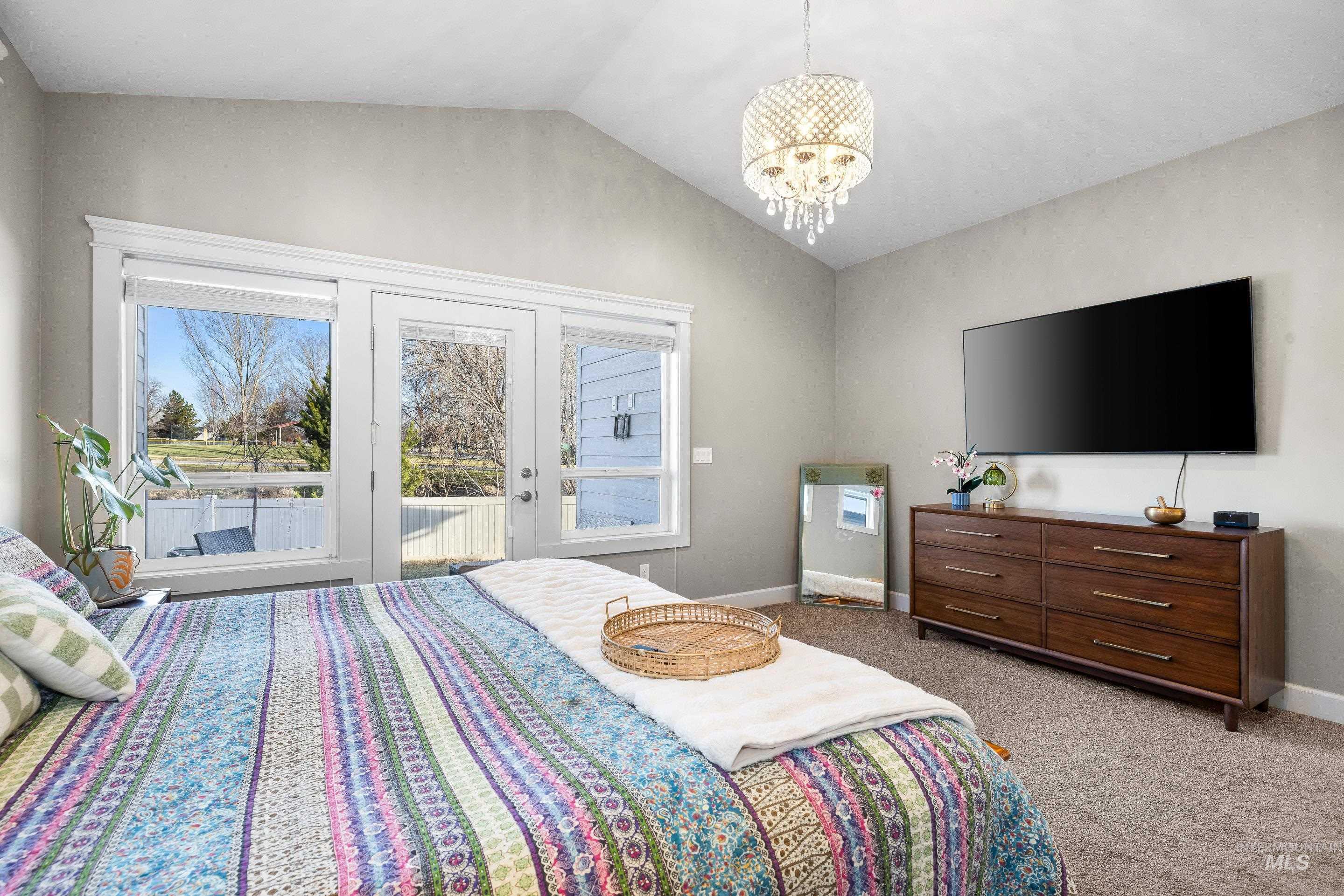 Bedroom with lofted ceiling, light colored carpet, access to outside, and a chandelier