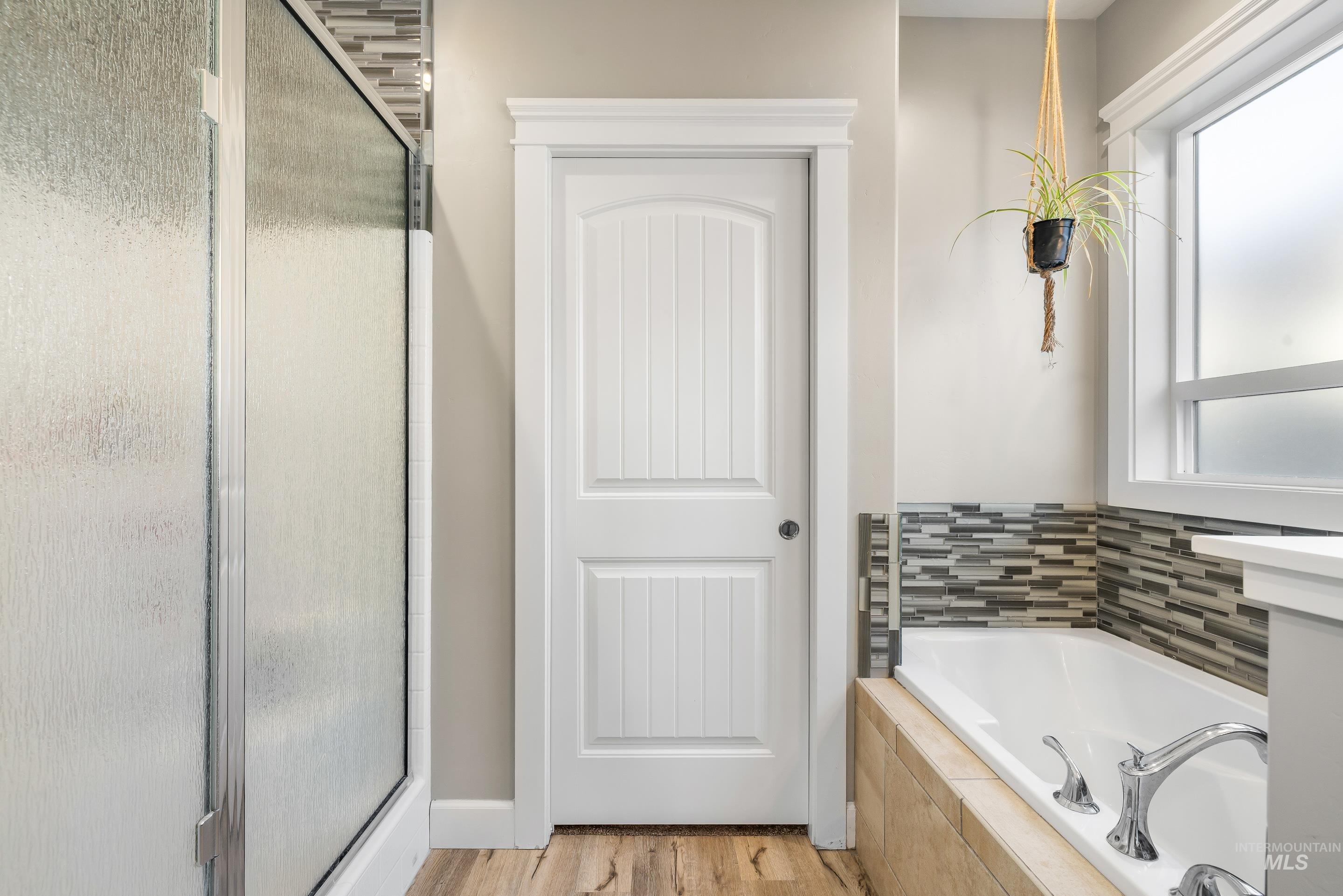 Full bath with a shower stall, a bath, and light wood-type flooring