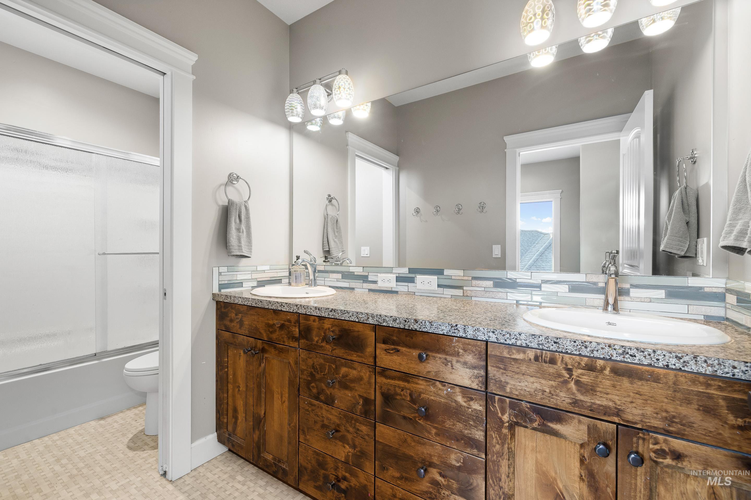 Bathroom with double vanity and shower / bath combination with glass door