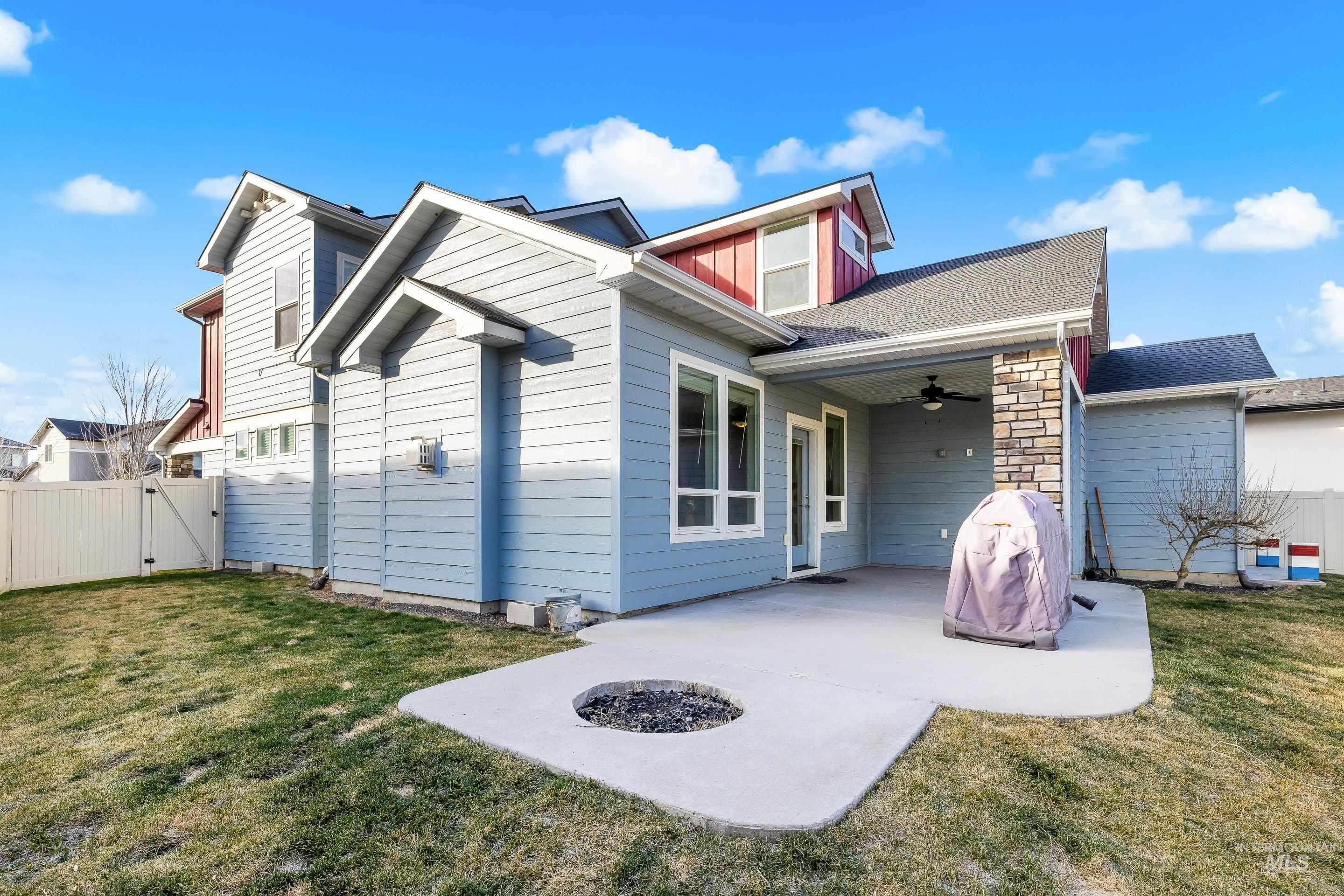 Back of house with a ceiling fan, a gate, a fire pit, a patio area, and stone siding