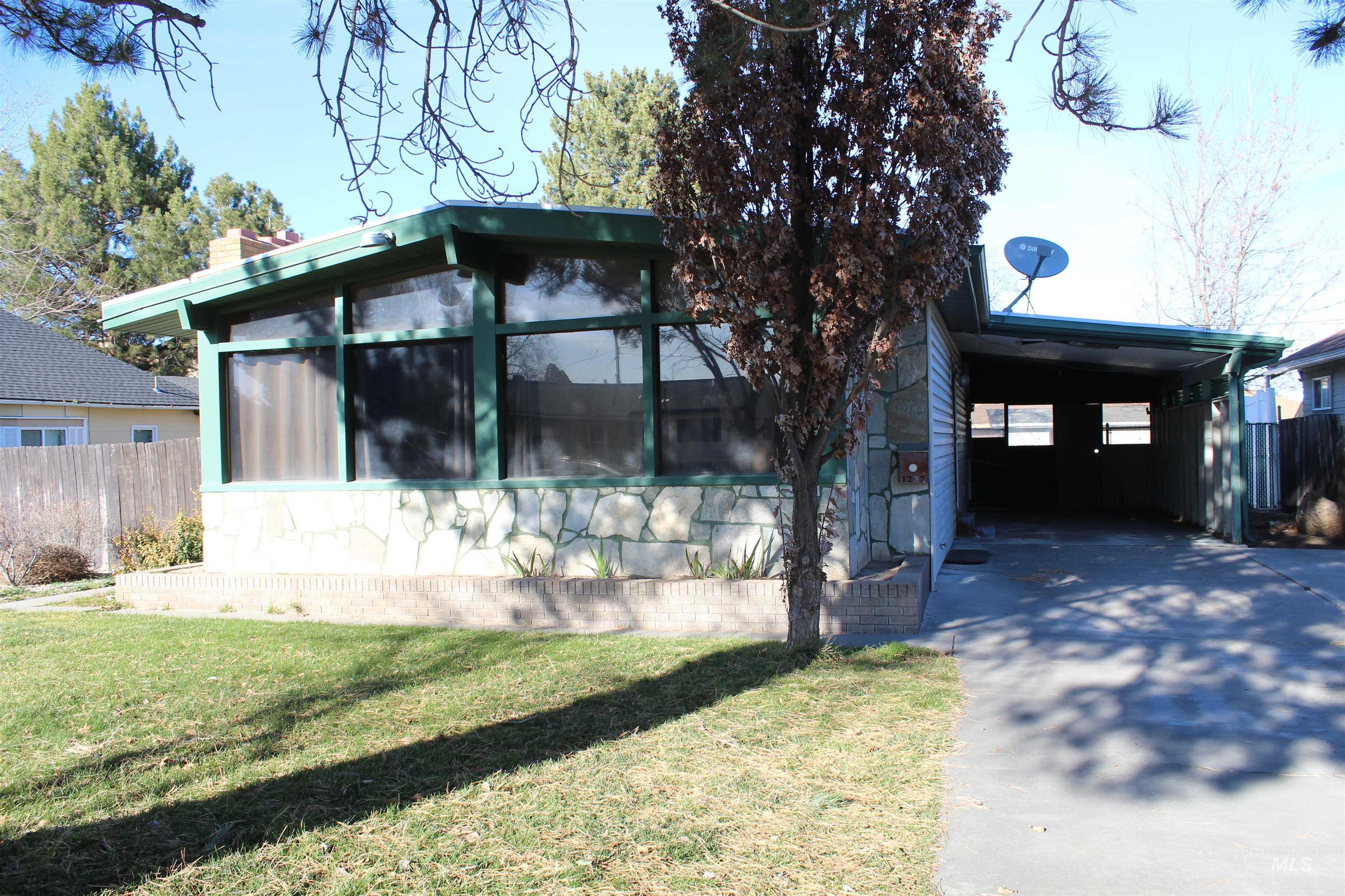 View of front of property featuring a carport, driveway, a chimney, and a sunroom