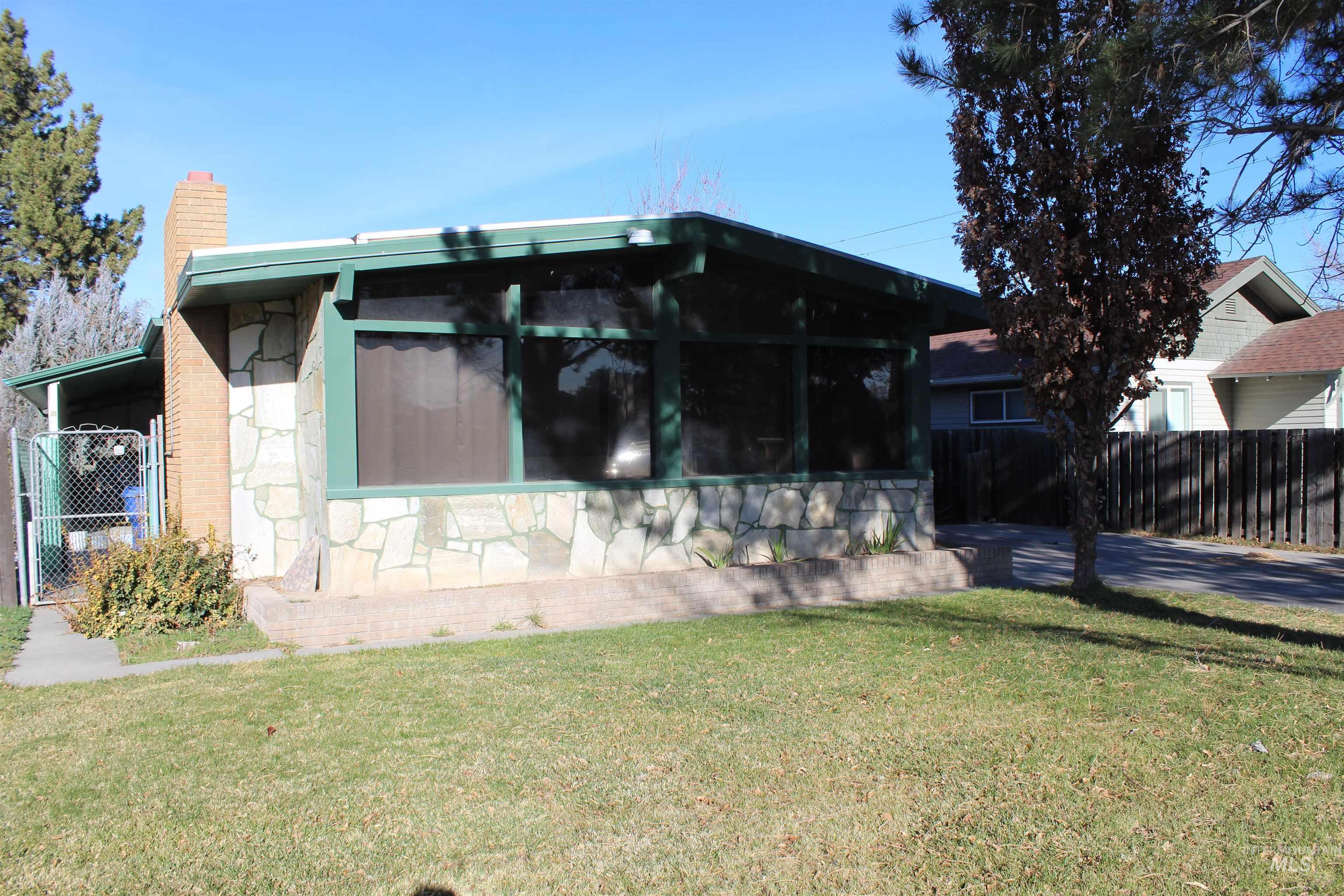 View of front of property with a chimney, a sunroom, and stone siding