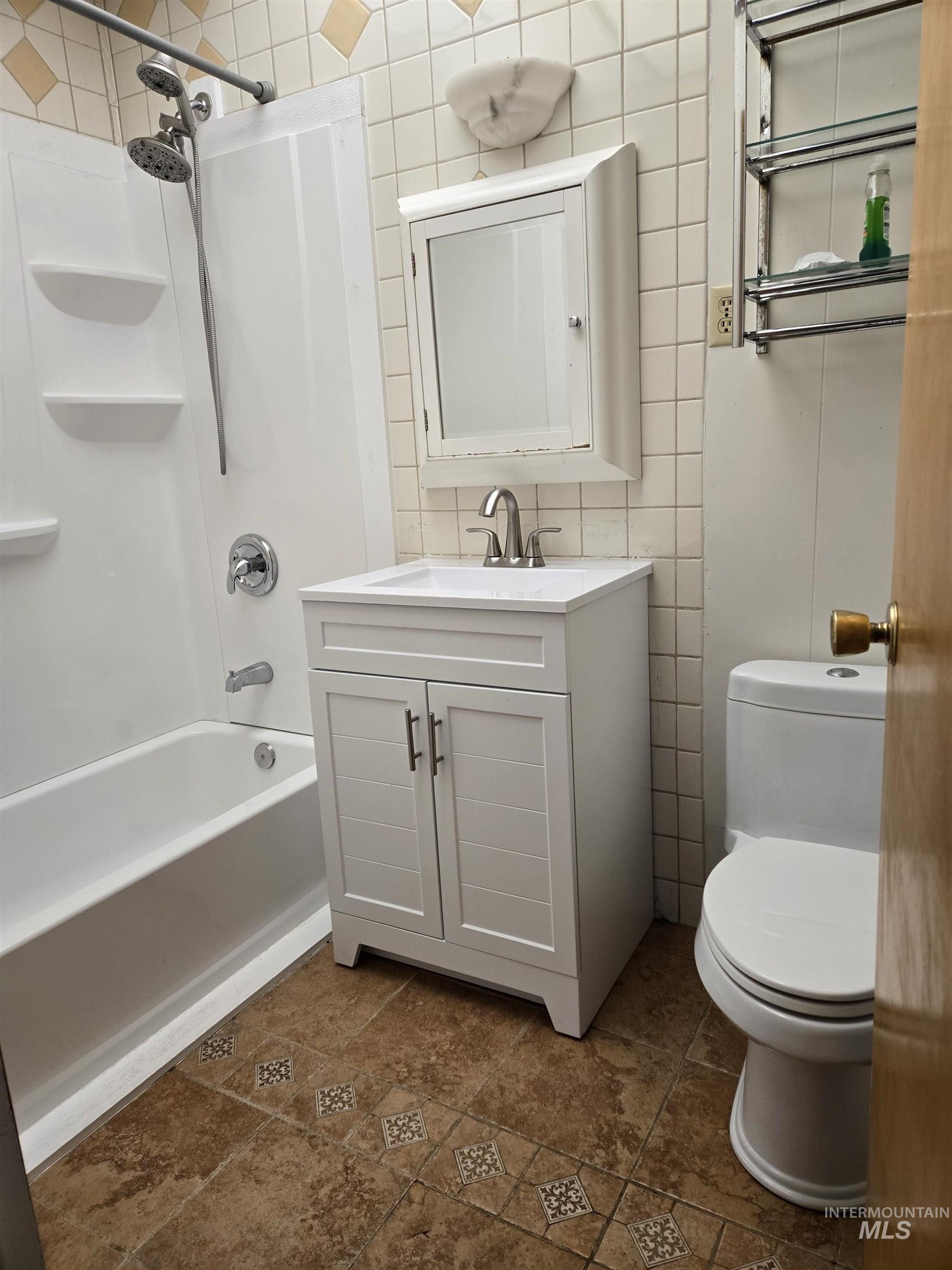 Full bathroom with bathing tub / shower combination, tile walls, and vanity