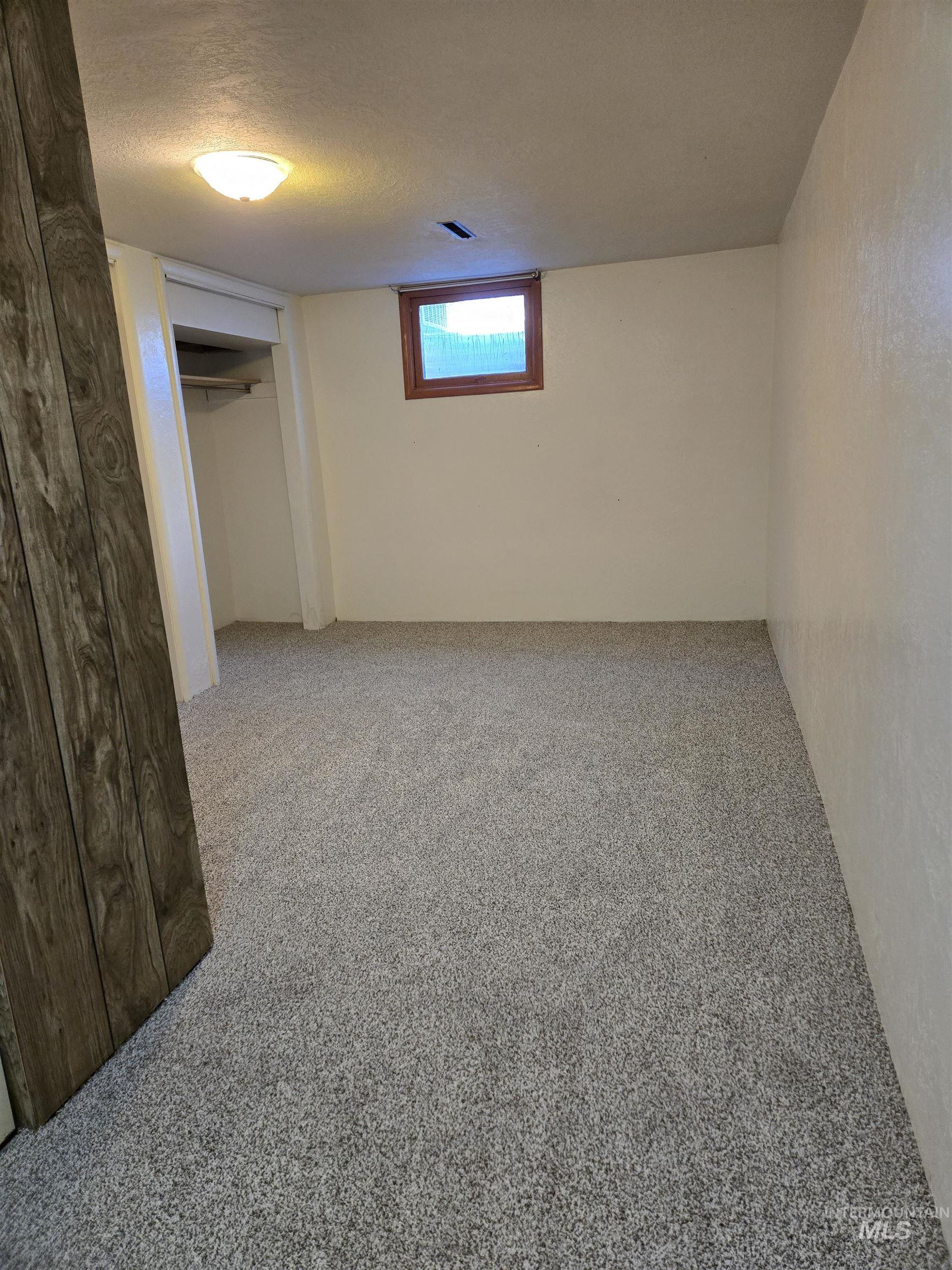Basement featuring light colored carpet and a textured ceiling