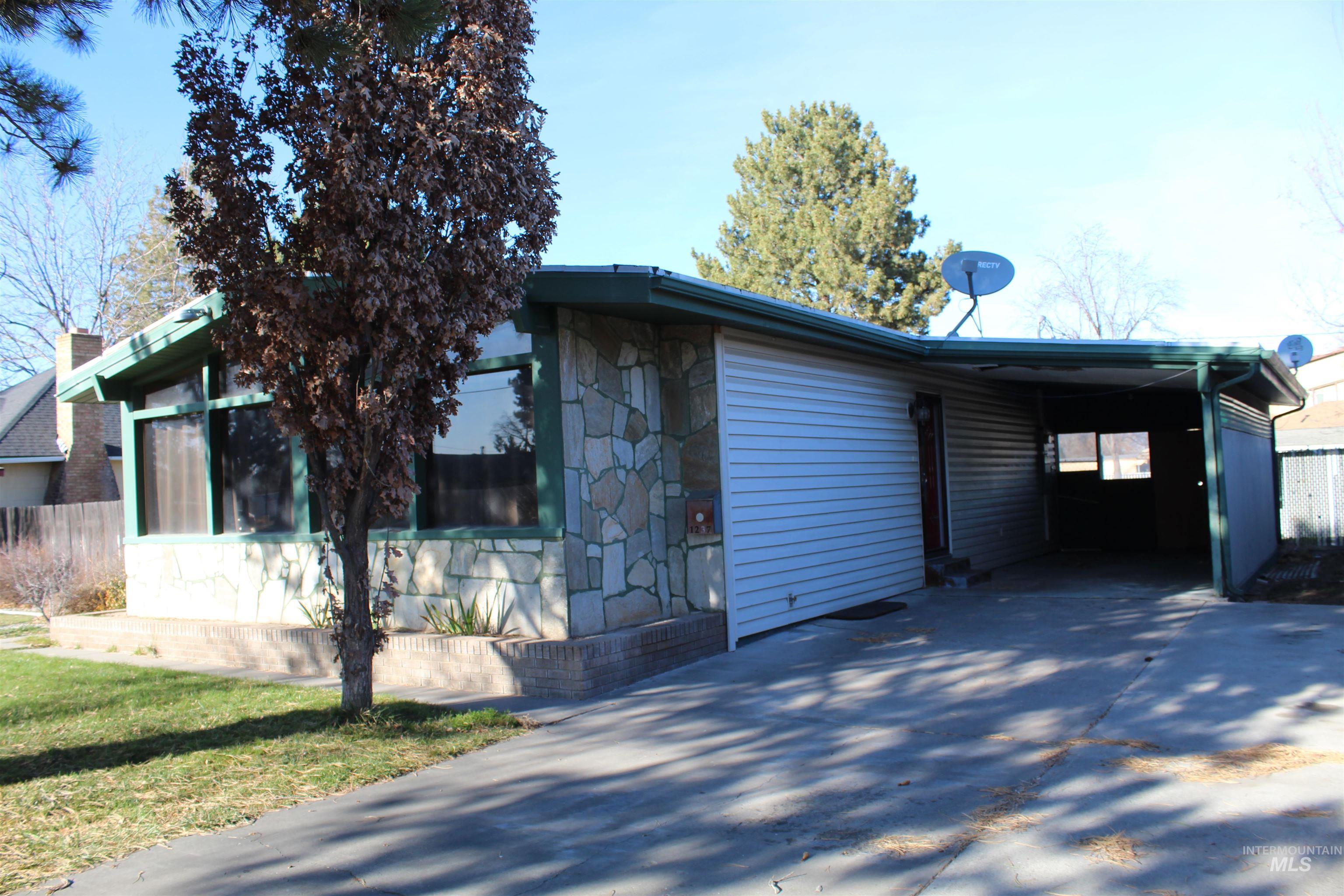 View of front of property featuring stone siding, driveway, and a carport