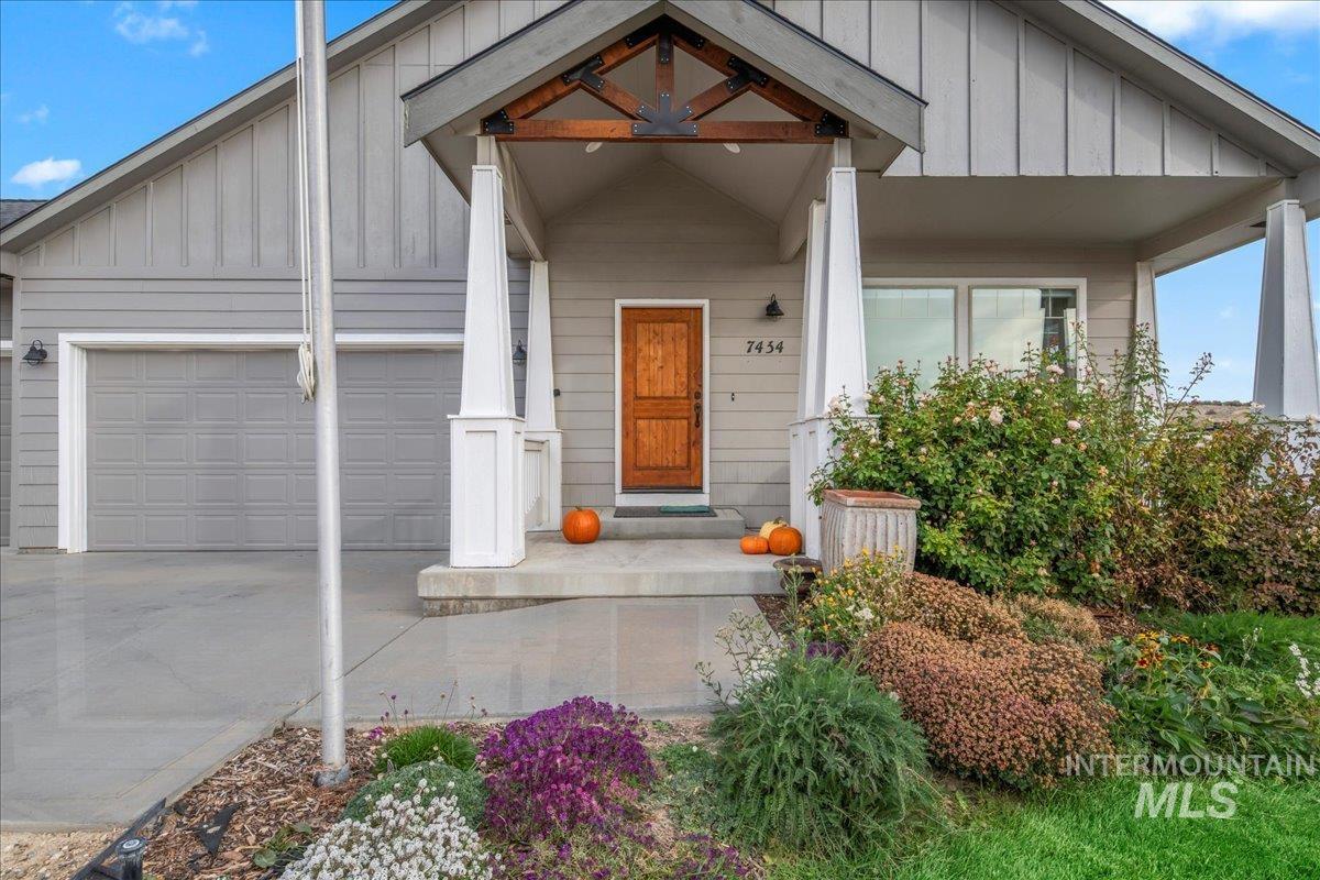 Property entrance featuring board and batten siding, a porch, driveway, and a garage