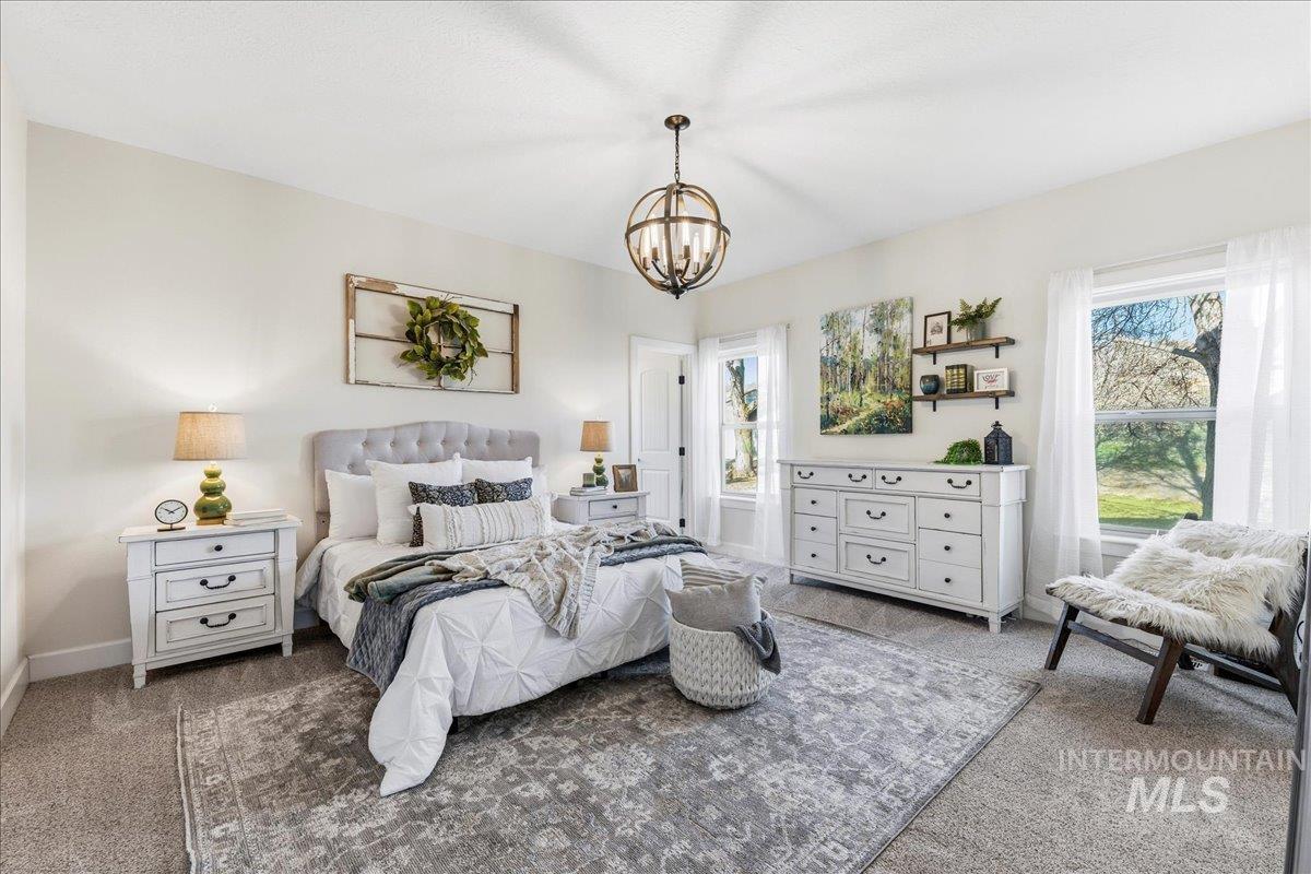 Bedroom with light carpet and a chandelier