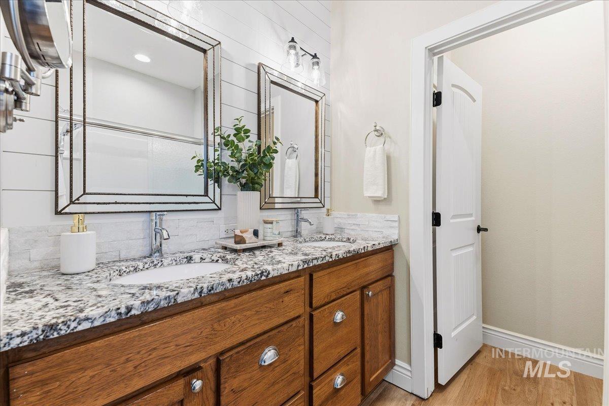 Bathroom featuring double vanity, light wood-style floors, and backsplash