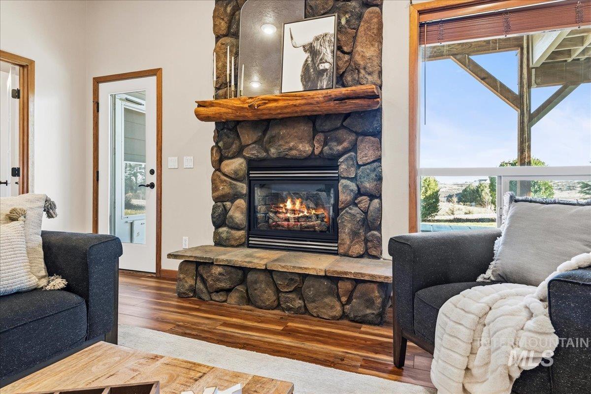 Living room with a stone fireplace, wood finished floors, and healthy amount of natural light