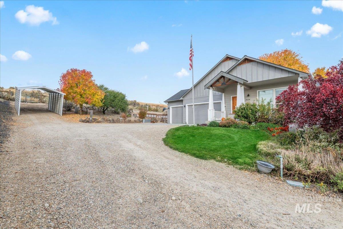 View of front facade featuring driveway, board and batten siding, and a front yard
