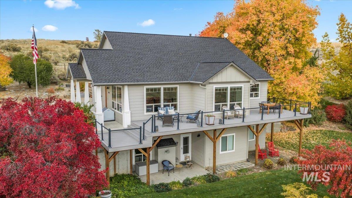 Back of property featuring a shingled roof, board and batten siding, and a patio