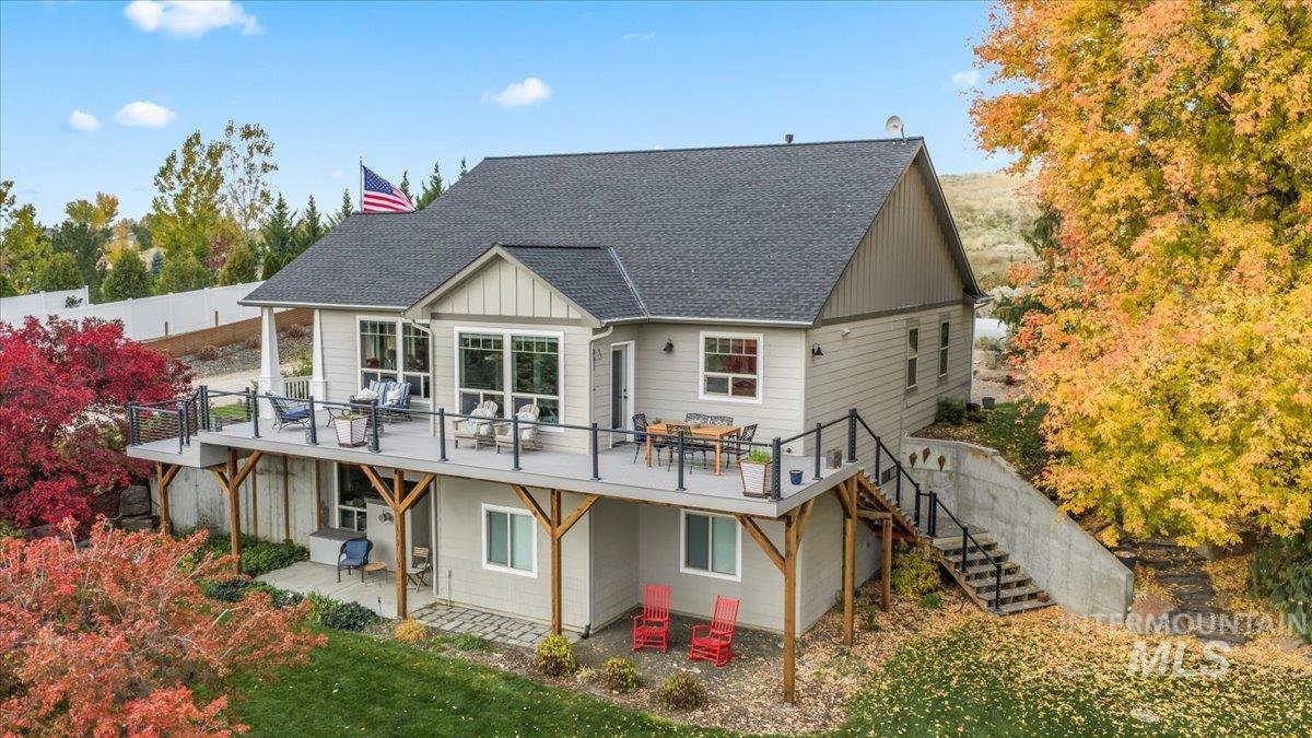 Rear view of property with a shingled roof, a patio area, stairway, board and batten siding, and outdoor dining area