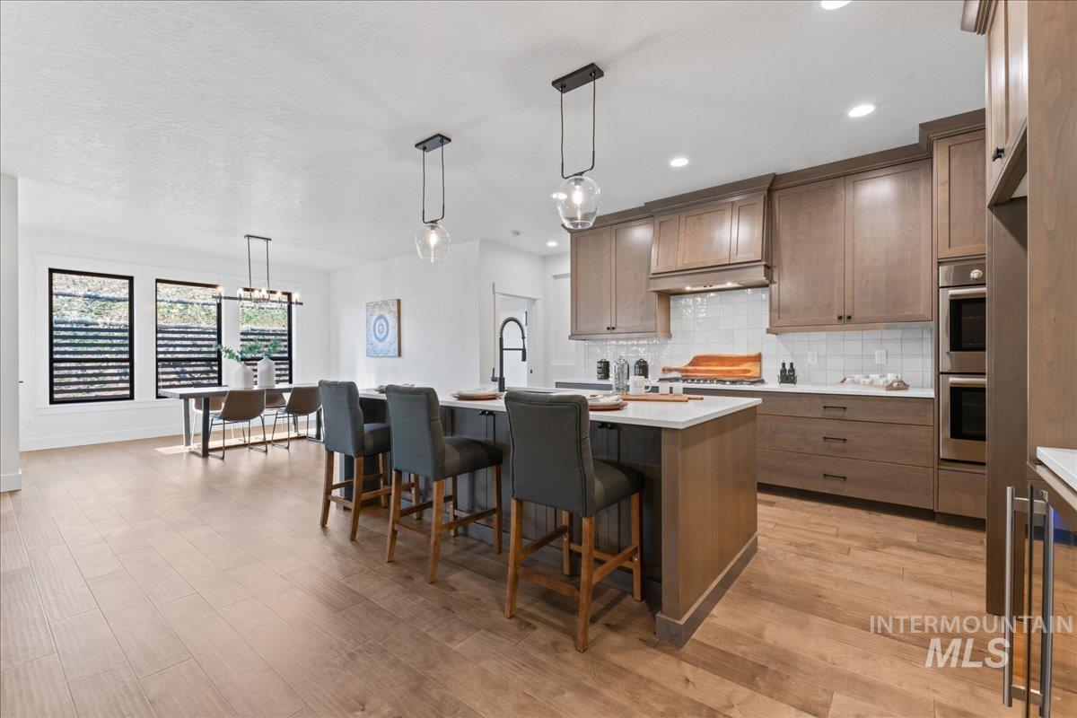 Kitchen featuring hanging light fixtures, a breakfast bar area, an island with sink, beverage cooler, and recessed lighting