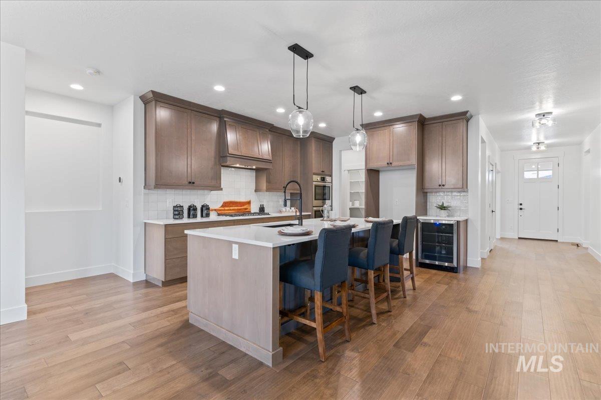 Kitchen with a kitchen breakfast bar, pendant lighting, an island with sink, light wood-style flooring, and recessed lighting