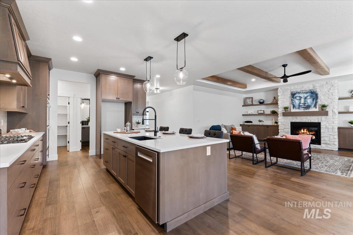 Kitchen featuring open floor plan, pendant lighting, dark wood-style flooring, premium range hood, and a kitchen island with sink