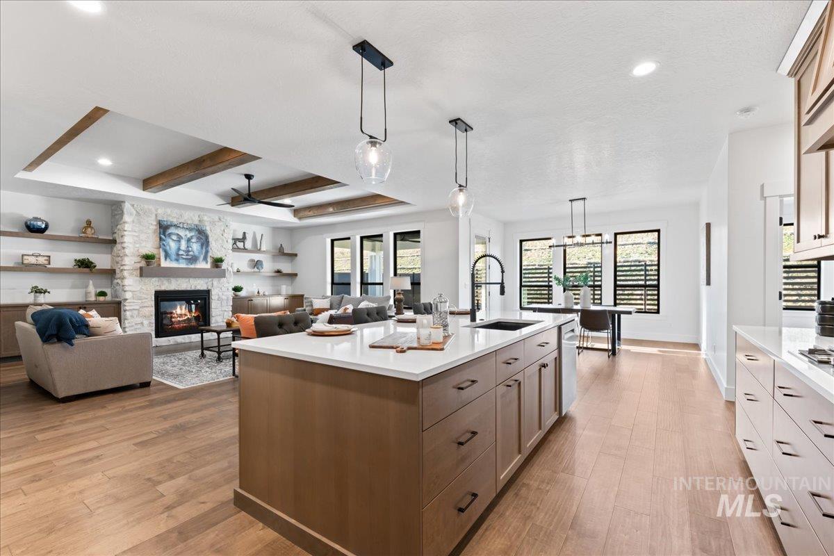 Kitchen with hanging light fixtures, light wood-type flooring, open floor plan, a fireplace, and a center island with sink