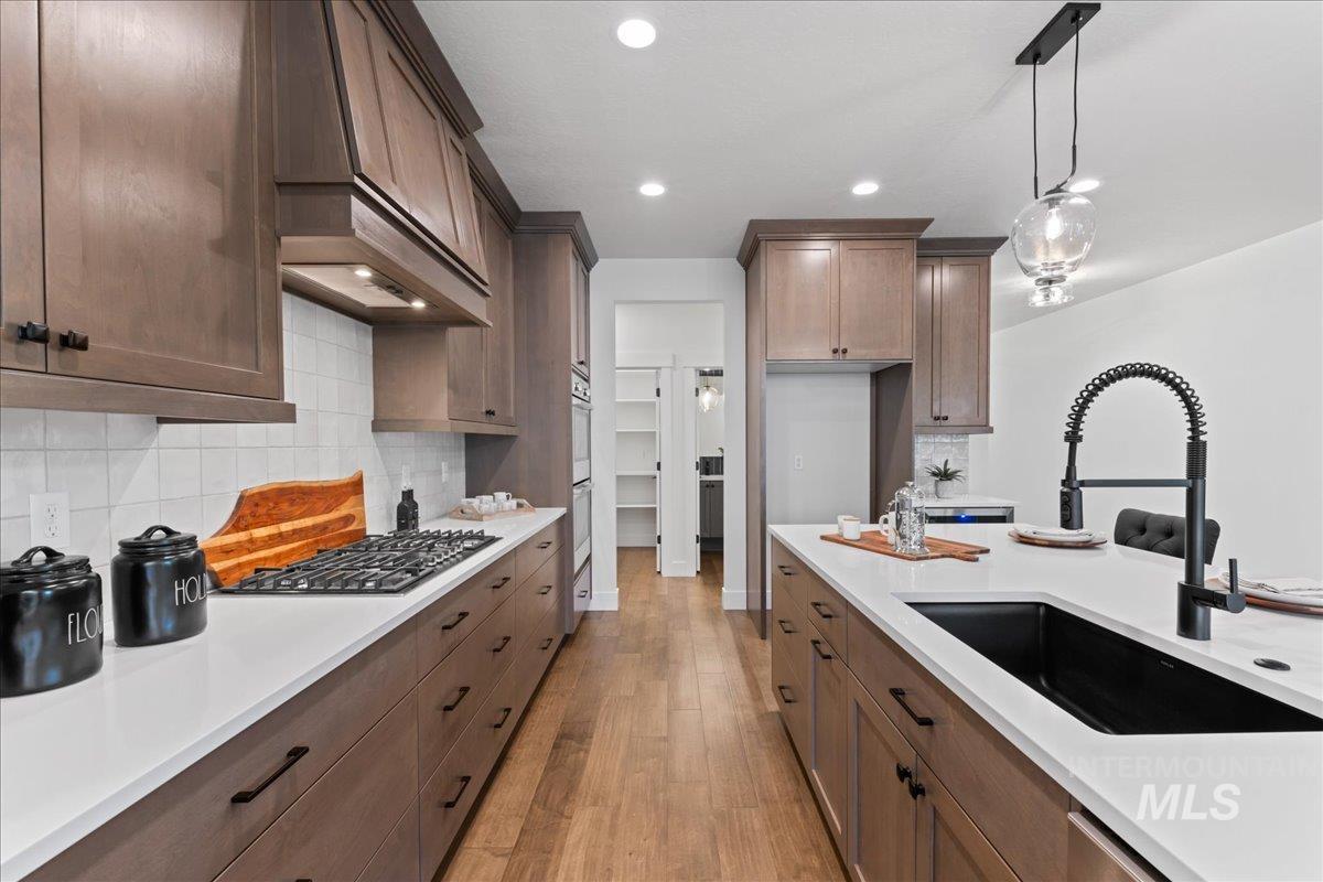 Kitchen featuring pendant lighting, tasteful backsplash, custom exhaust hood, light wood-style flooring, and recessed lighting