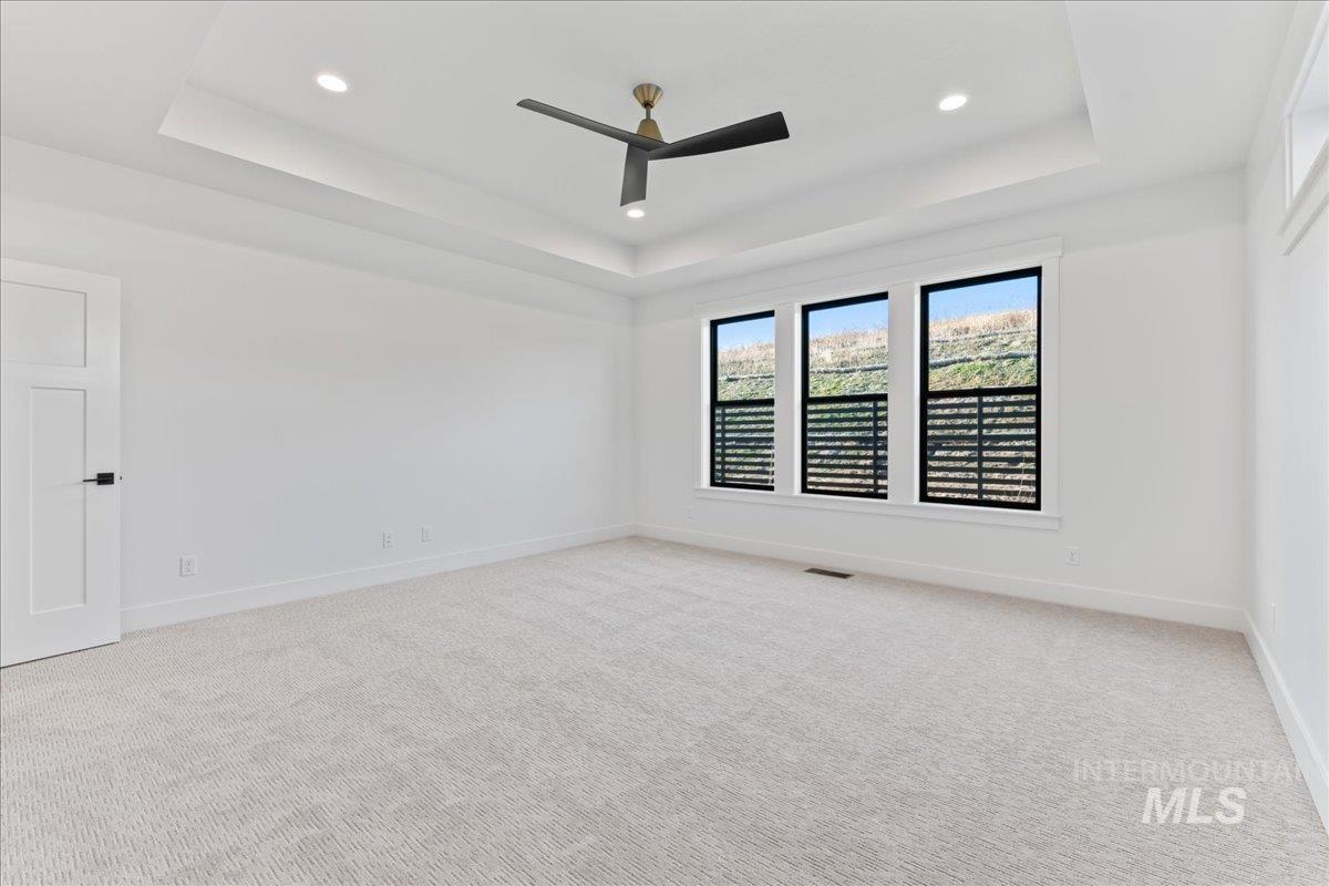 Spare room with light carpet, a raised ceiling, ceiling fan, and recessed lighting