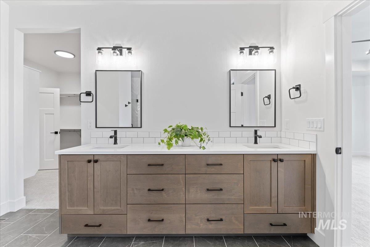 Full bathroom featuring double vanity and baseboards