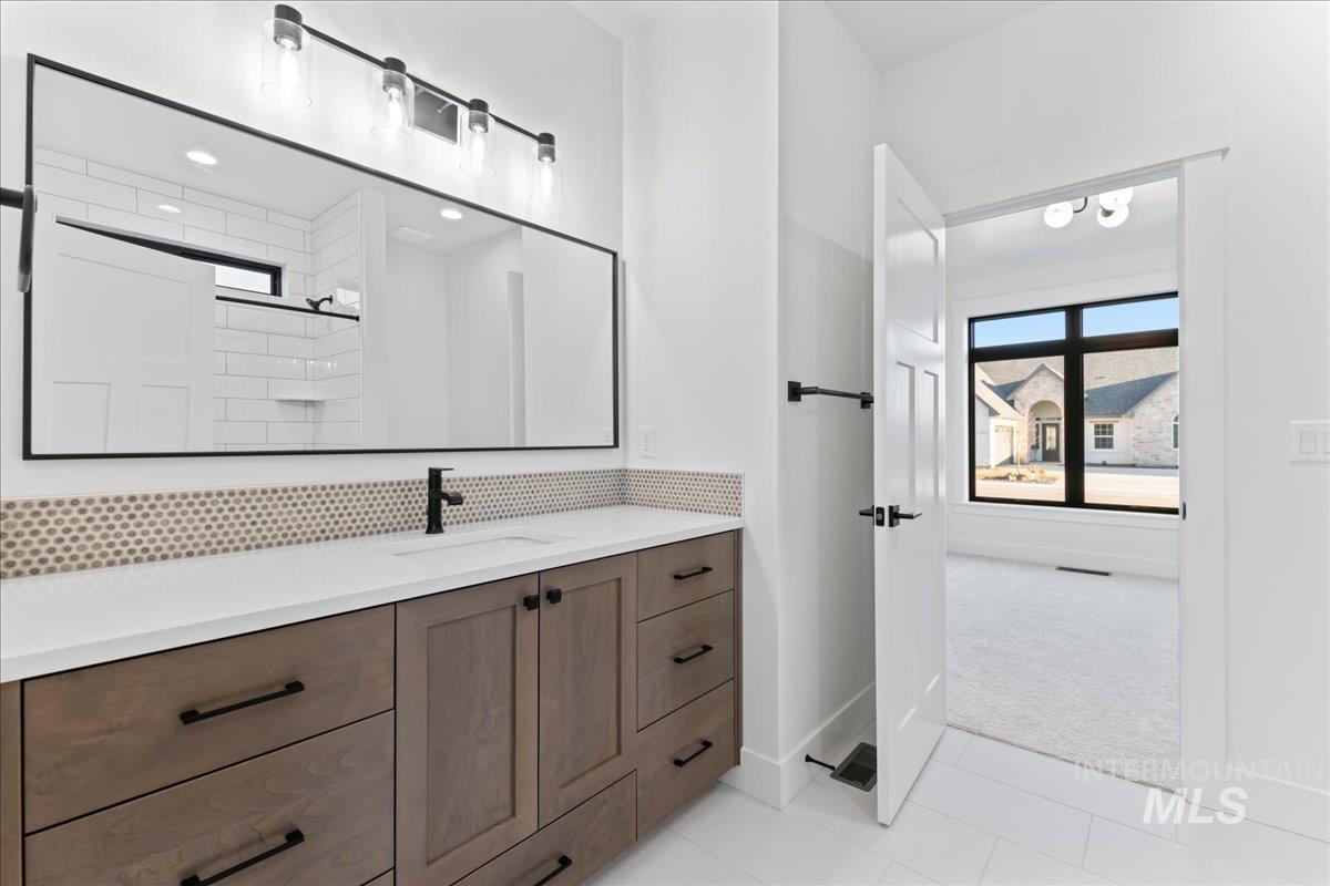 Full bath with plenty of natural light, vanity, decorative backsplash, and light tile patterned floors